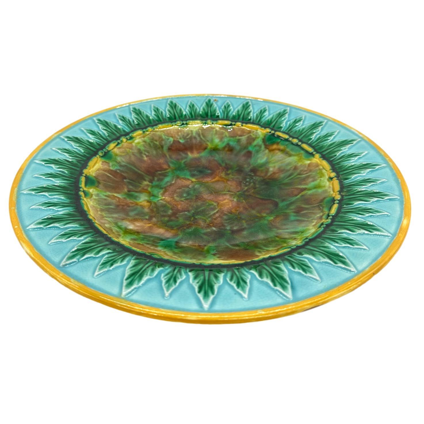 George Jones Majolica Dish, the center with tortoiseshell mottling, bordered with green-glazed acanthus leaves on a turquoise-glazed ground, the inner and outer border rims glazed in yellow ocher, the reverse with impressed 'GJ' monogram and painted
