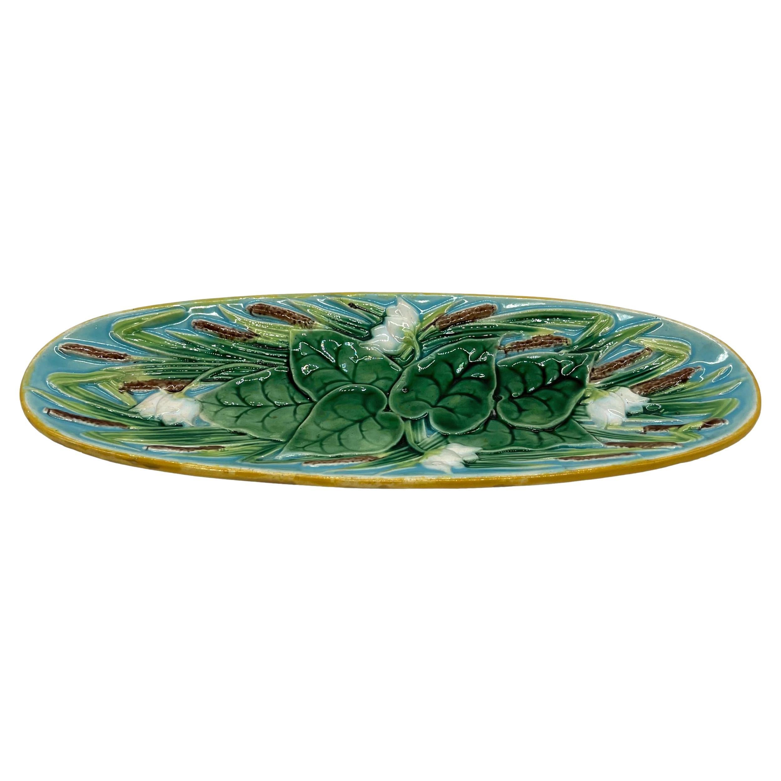 A George Jones Majolica 10-inch Oval Pen Tray, with green-glazed relief-molded lily pads with white blossoms and naturalistically glazed bullrushes on turquoise-glazed water forming the ground, with a yellow ocher rim, the reverse glazed in brown