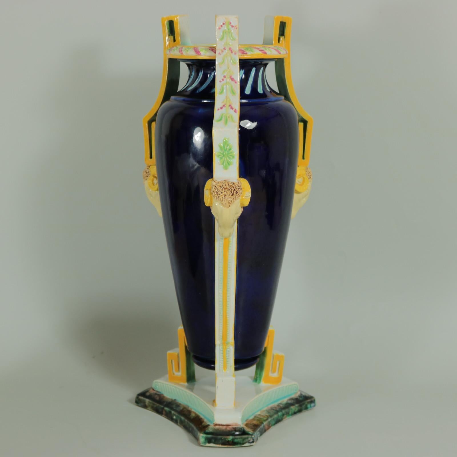 George Jones Majolica vase which features ram heads supporting the elaborate handles. Berry decoration to the handles. Colouration: cobalt blue, white, yellow, are predominant. Bears a pattern number, 'W'. Book reference ,'George Jones Ceramics