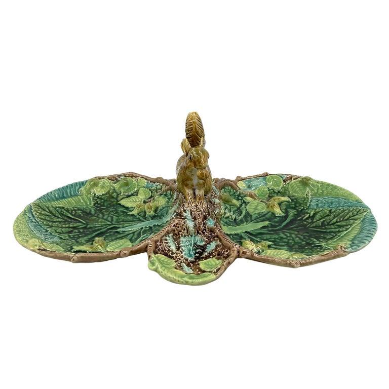 A George Jones Majolica Quadrilobed sandwich tray, molded with leaves, ferns, and hazelnut blossoms glazed in green, chartreuse, and turquoise on a rustic ground, the handle formed as an applied naturalistic model of a crouching squirrel eating a