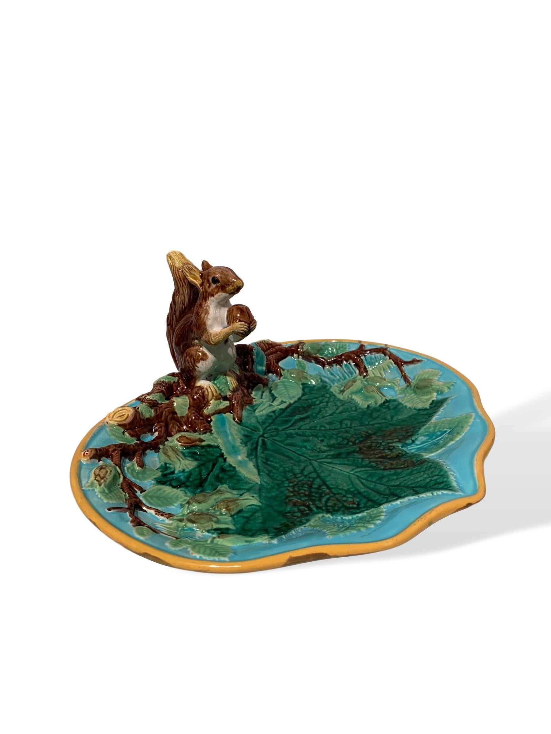 George Jones Majolica squirrel nut dish, English, circa 1870, molded with leaves, ferns and hazelnut blossoms, with applied naturalistic model of a crouching squirrel with a hazelnut in his mouth. This beautifully glazed and crisply molded dish has