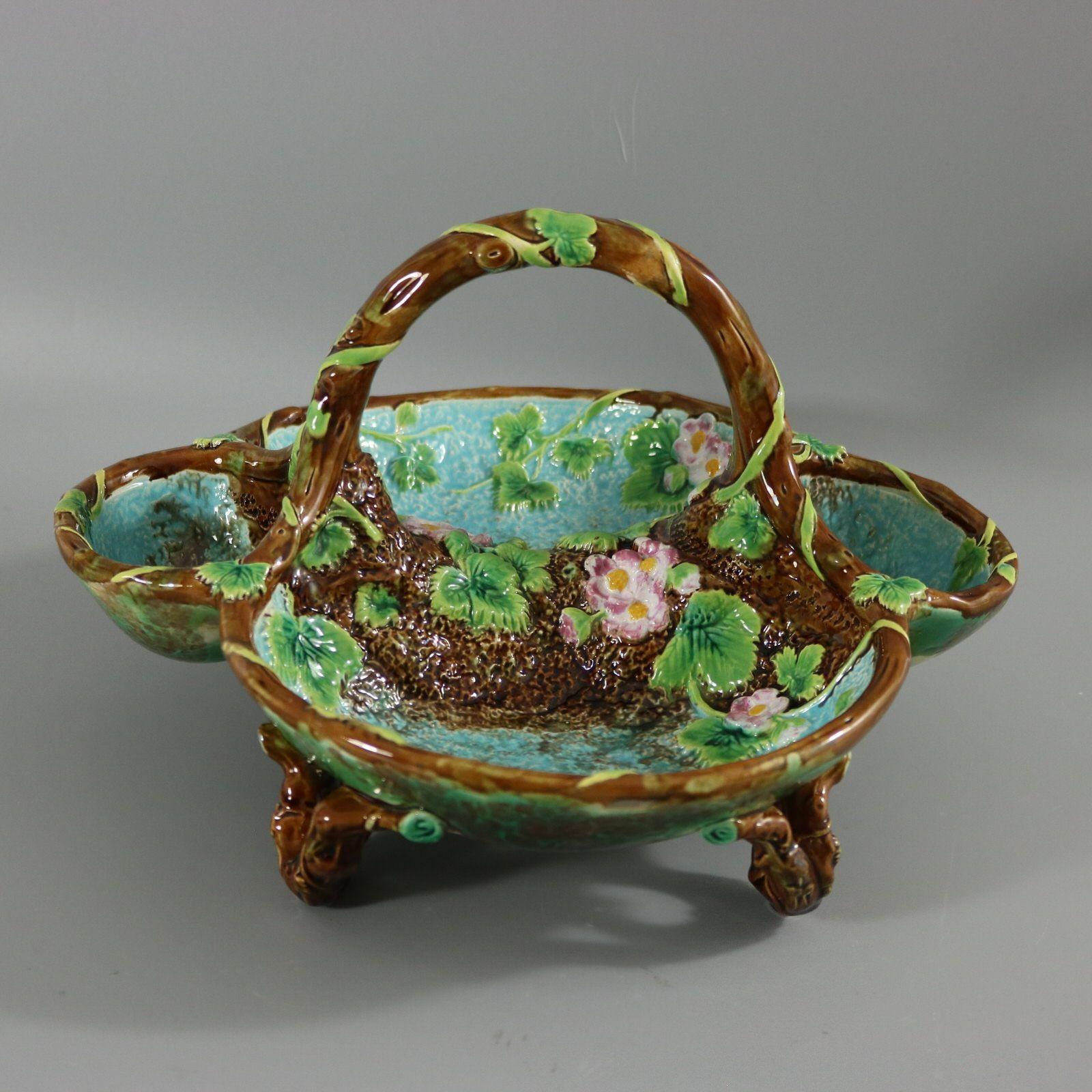 George Jones Majolica strawberry server basket which features a mossy textured ground decorated with strawberry plant leaves and flowers. Naturalistic twig molding around the rim, which also forms the handle and the feet. Colouration: turquoise,