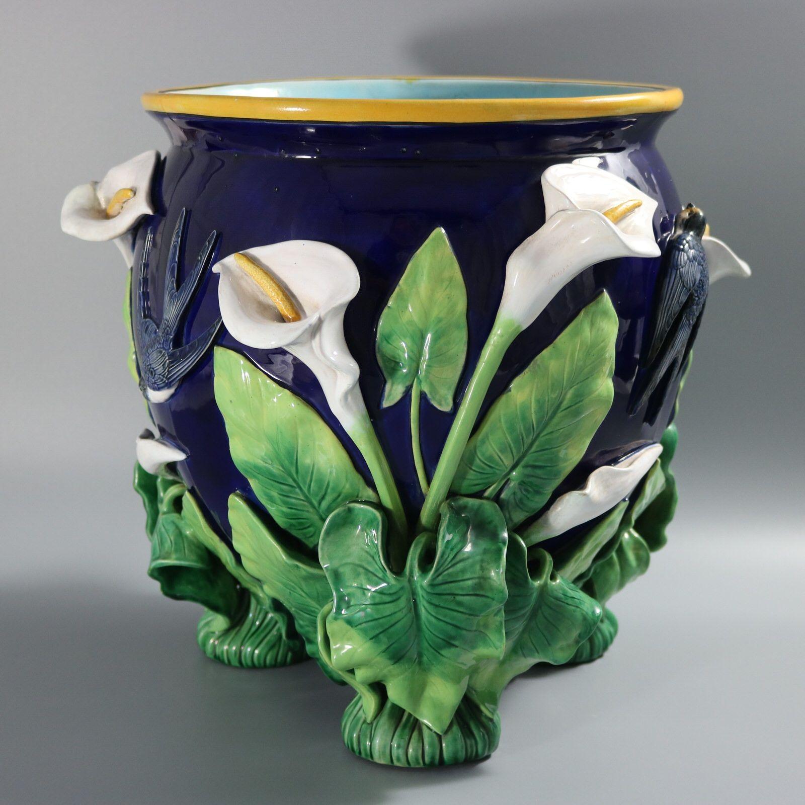 George Jones Majolica jardinière which features swallows swooping amongst calla lilies. The three feet are molded in the form of calla lilies with the leaves and flowers deeply and intricately modelled. Cobalt blue ground version. Colouration:
