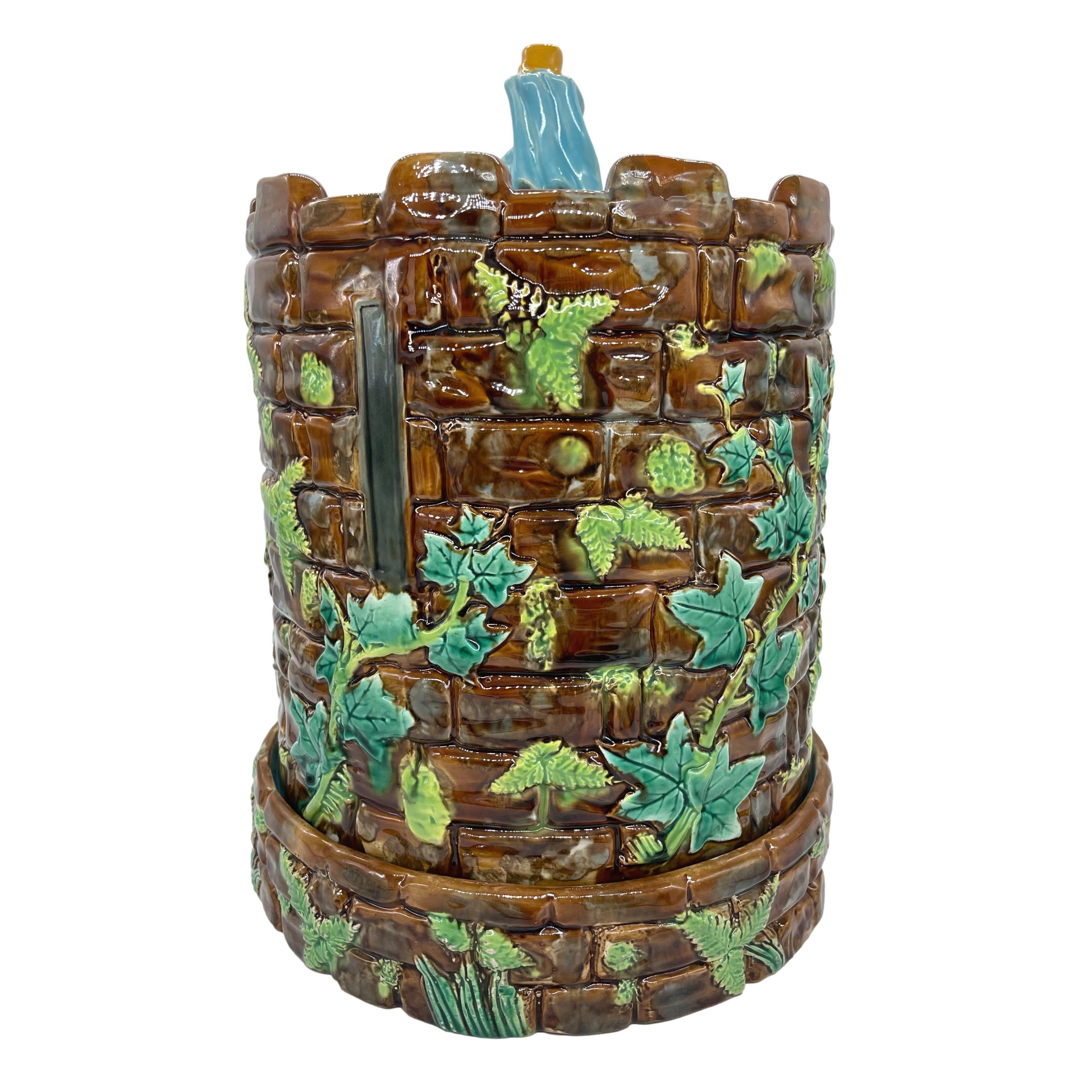 George Jones Majolica 'Tower Stilton' Dish Cheese Keeper and stand, the relief molded cover and base formed as a fortified castle tower (keep), with mossy stones and arrow slits realistically rendered, with trailing green-glazed ivy and ferns, with