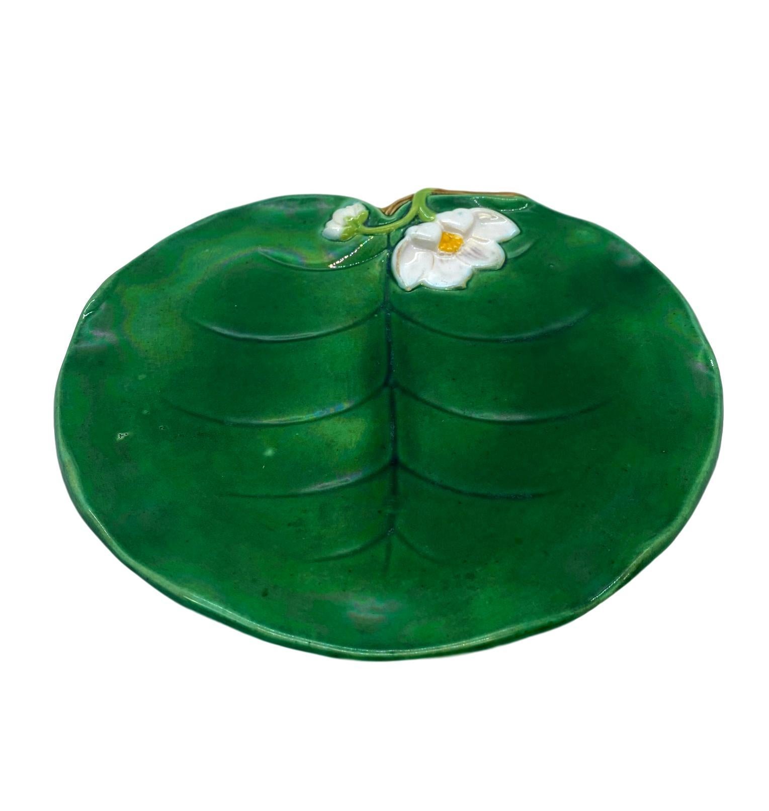 George Jones Majolica Water Lily plate glazed in lush greens, with a relief-molded lily flower, English, 1877. 
Marks to reverse: 'GJ' Monogram; British Registry Lozenge for 9 March 1869, the date the pattern was registered; George Jones date