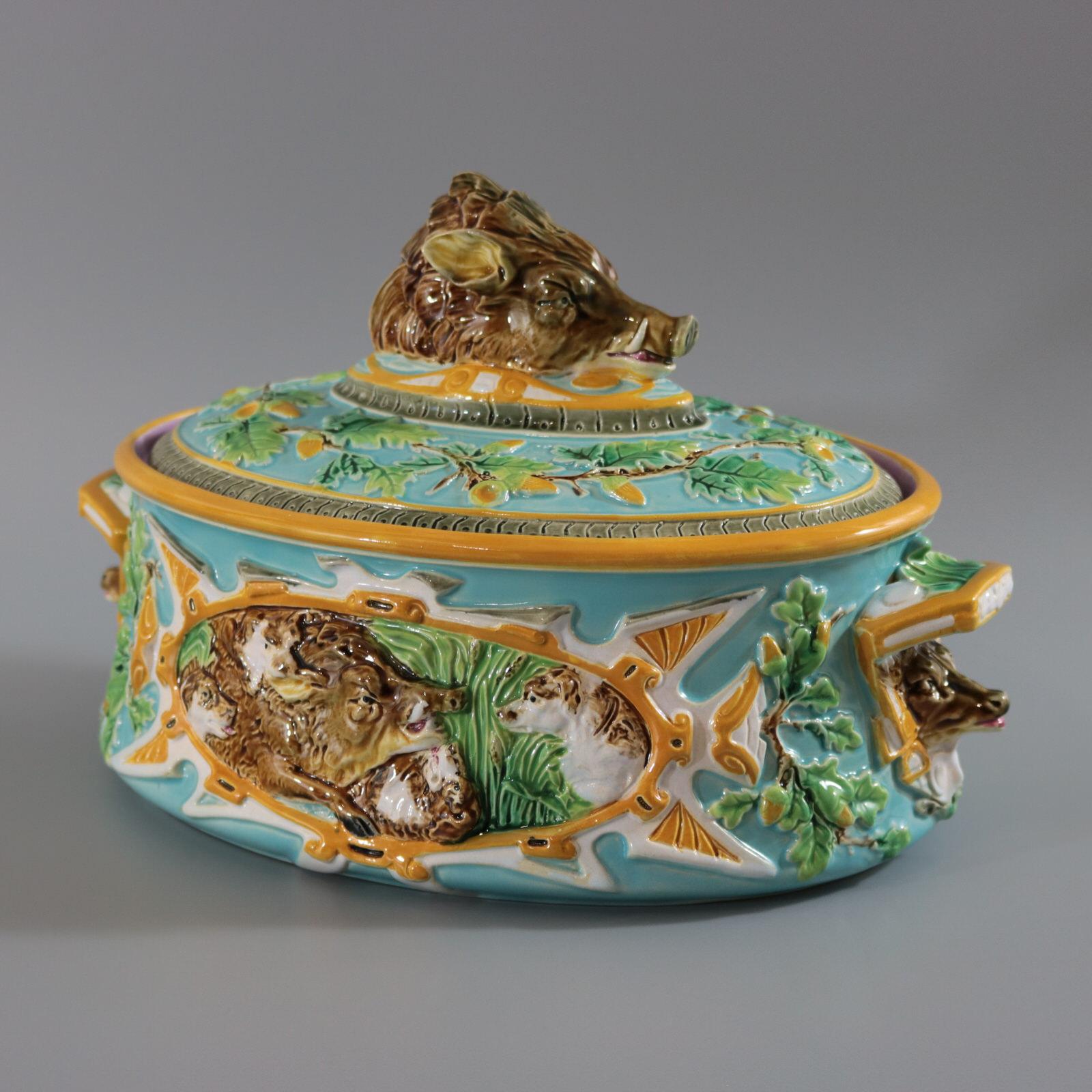 George Jones Majolica game pie dish which features the lid with a knop modelled as a wild boar head, an oak leaf and acorn border. The dish has handles at either end, with stag heads underneath. Panels on the sides depict a wild boar being hunted by