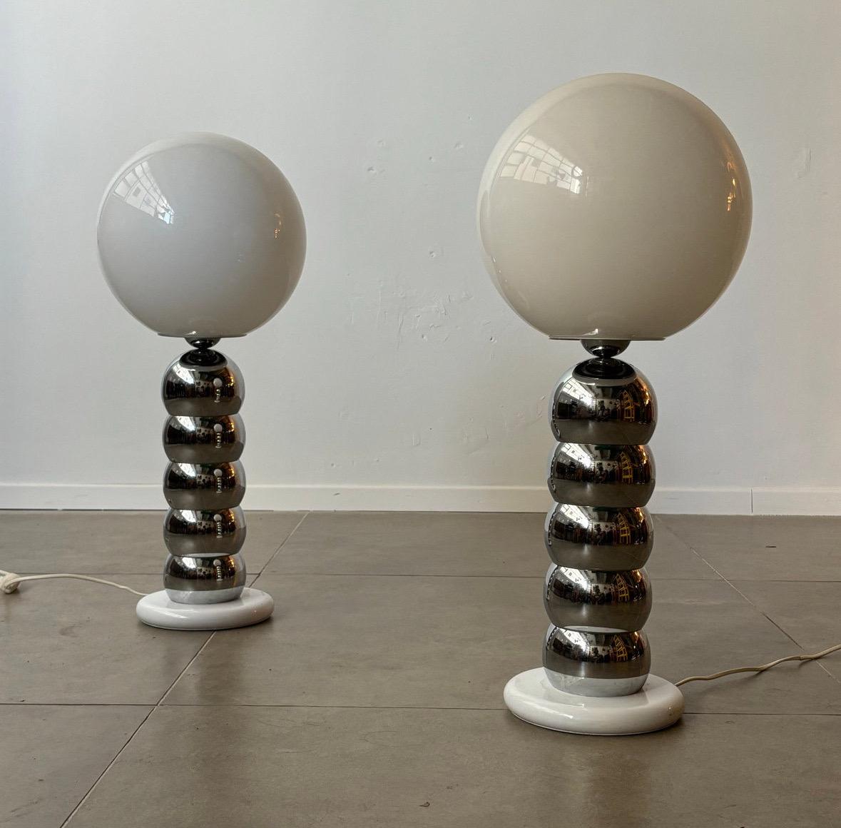 This striking pair of 1970s chrome stacked ball lamps, attributed to George Kovacs, showcases a playful yet sleek design. The lamps feature a series of polished chrome spheres, stacked one on top of the other in a cascading form reminiscent of a