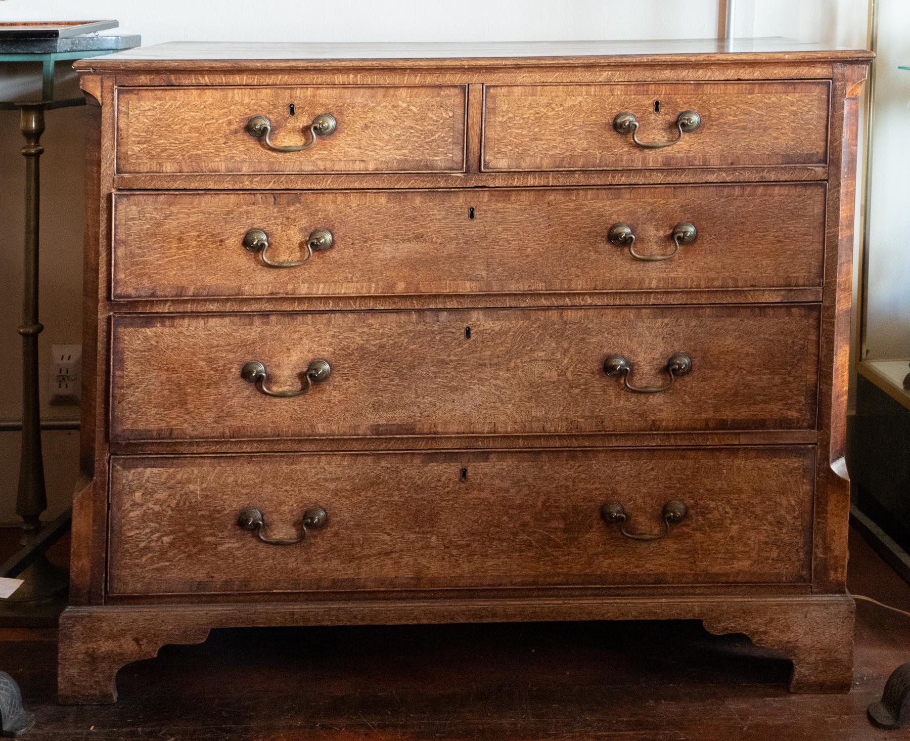 George III / Chippendale Oak Chest of Drawers. Quarter sawn oak, cross banding with canted corners. Very original condition. Retains the original brasses, steel locks and bracket feet. Old dry leather looking patina. Some shrinkage of the drawers,