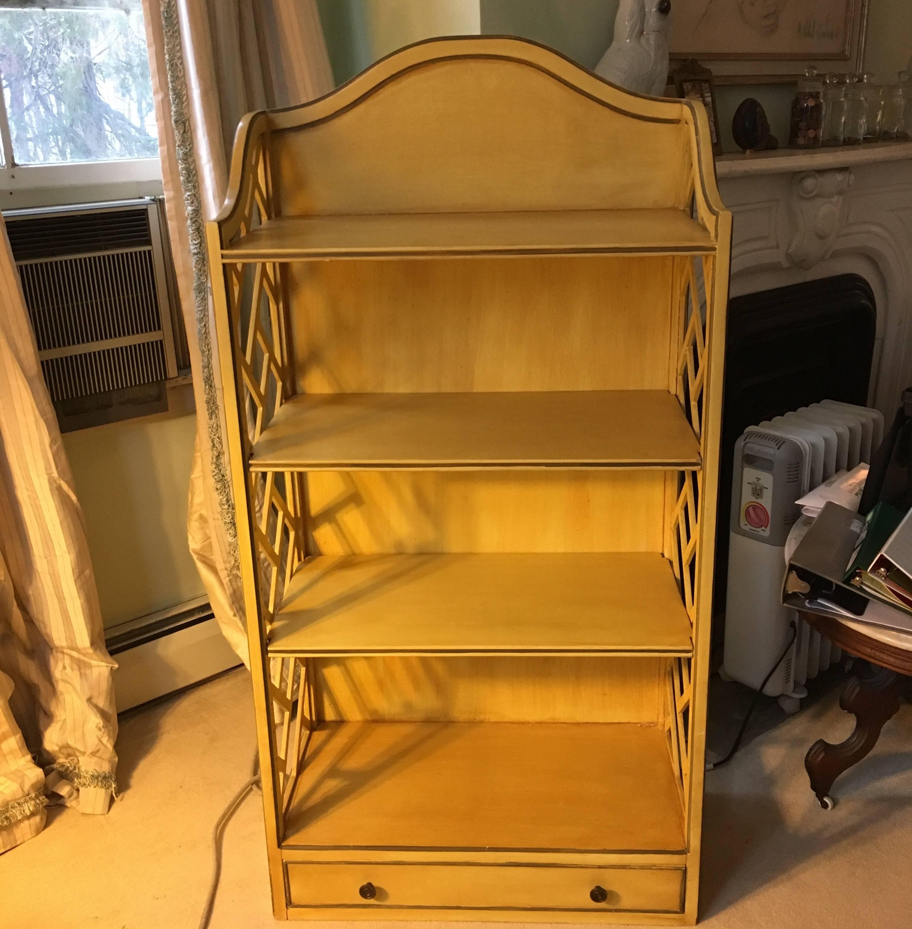 George III-style yellow painted wood bookshelf. Three ample shelves over a drawer at the bottom.
Some scratches on the top shelf, negligible and unseen with books or bibelots. Grey painted stringing
on edges.
 