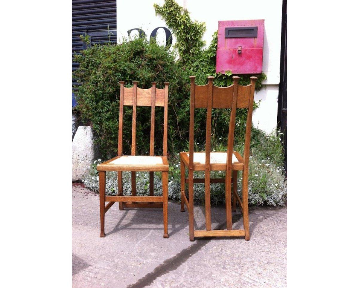 George Montague Ellwood. Made by J S Henry. 
A pair of matching oak dining chairs with throne like capped tops and wonderful sweeping back supports on tapering square legs. 
Priced individually at £1800 each.
 