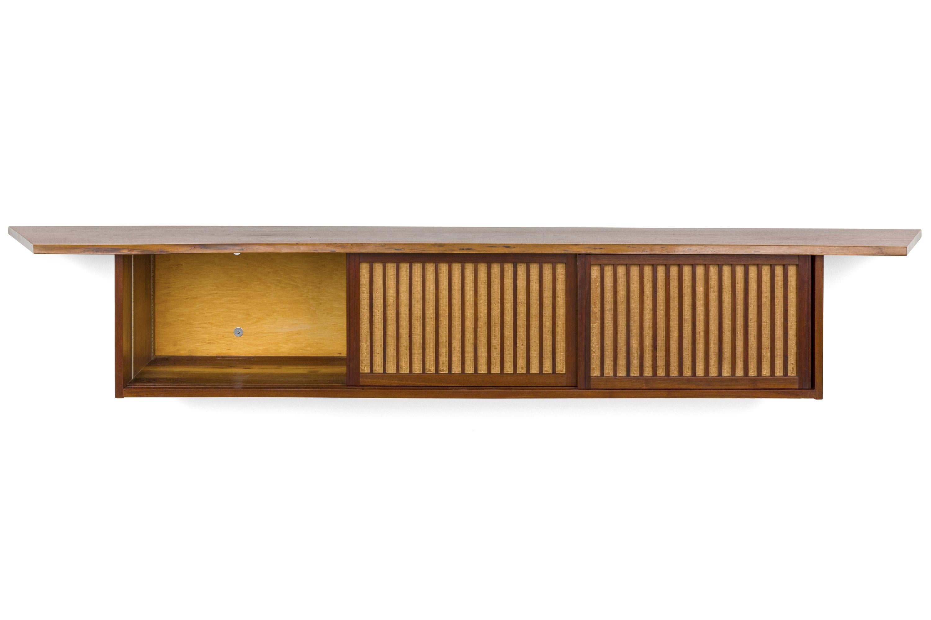 An outstanding example of Nakashima's distinctive hanging cabinets. It has an uncommon interior with several drawers as well as adjustable shelving. It's size alone is quite impressive. Size: 10' wide.
