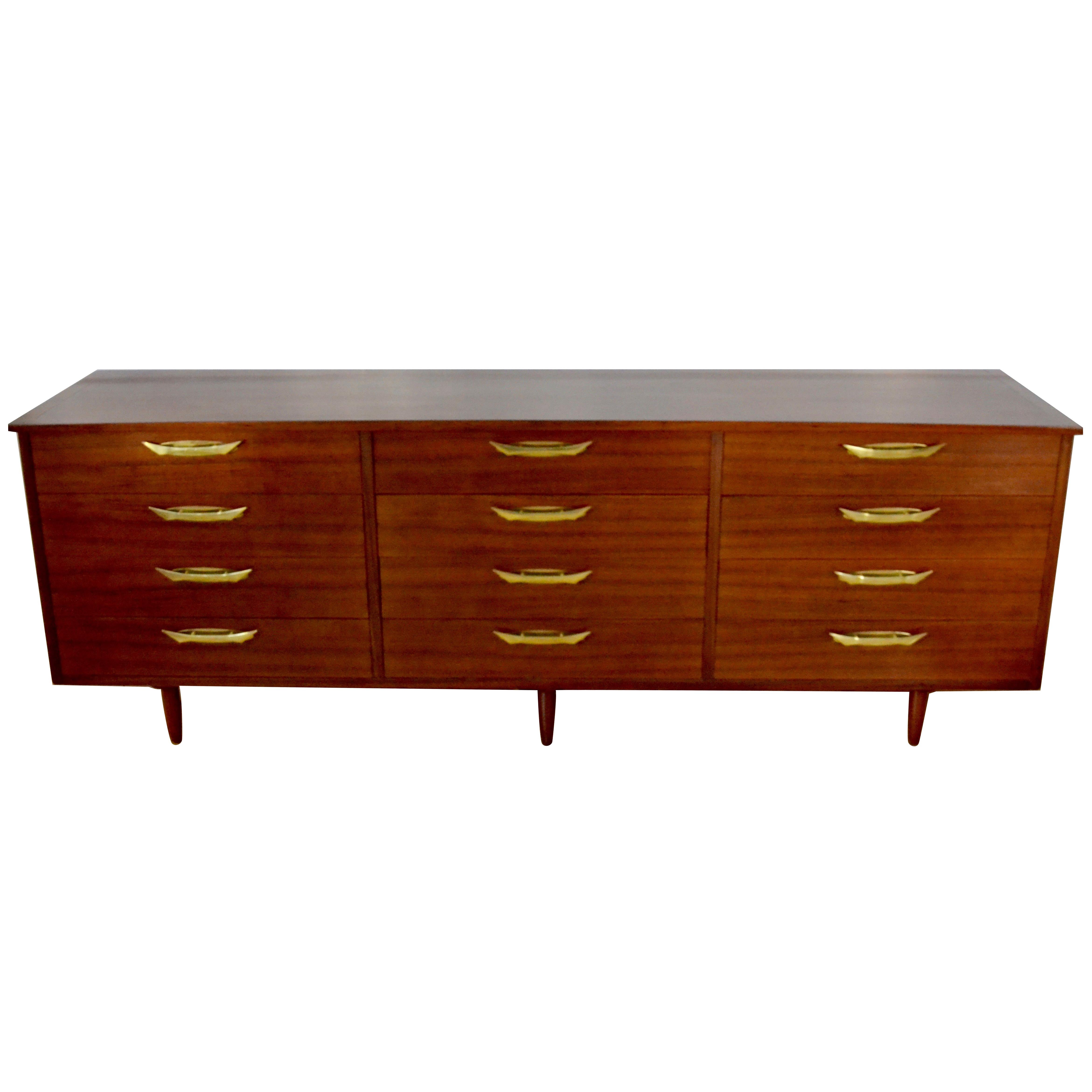  George Nakashima walnut 12-drawer dresser part of his Origins line manufactured by Widdicomb dated 1960. 
The dresser case is American walnut with Bay Laurel drawers and polished bronze drawer pulls..
The top is a graceful overhang running the