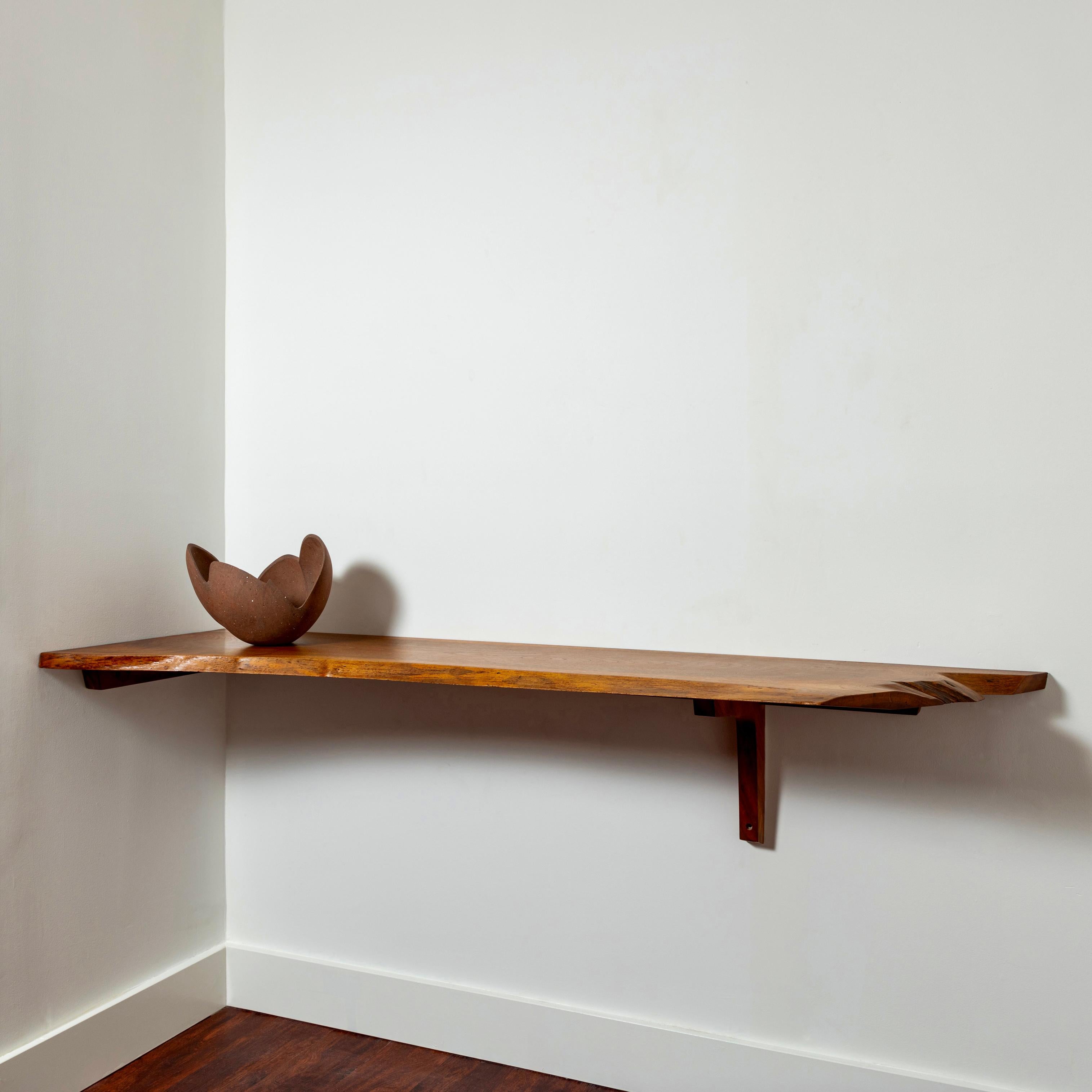 A corner-mounted counter shelf or floating console table by George Nakashima comprising a single slab in American black walnut with two free edges, signed and dated 1971 to the underside. From the estate of the original owners, it is accompanied by