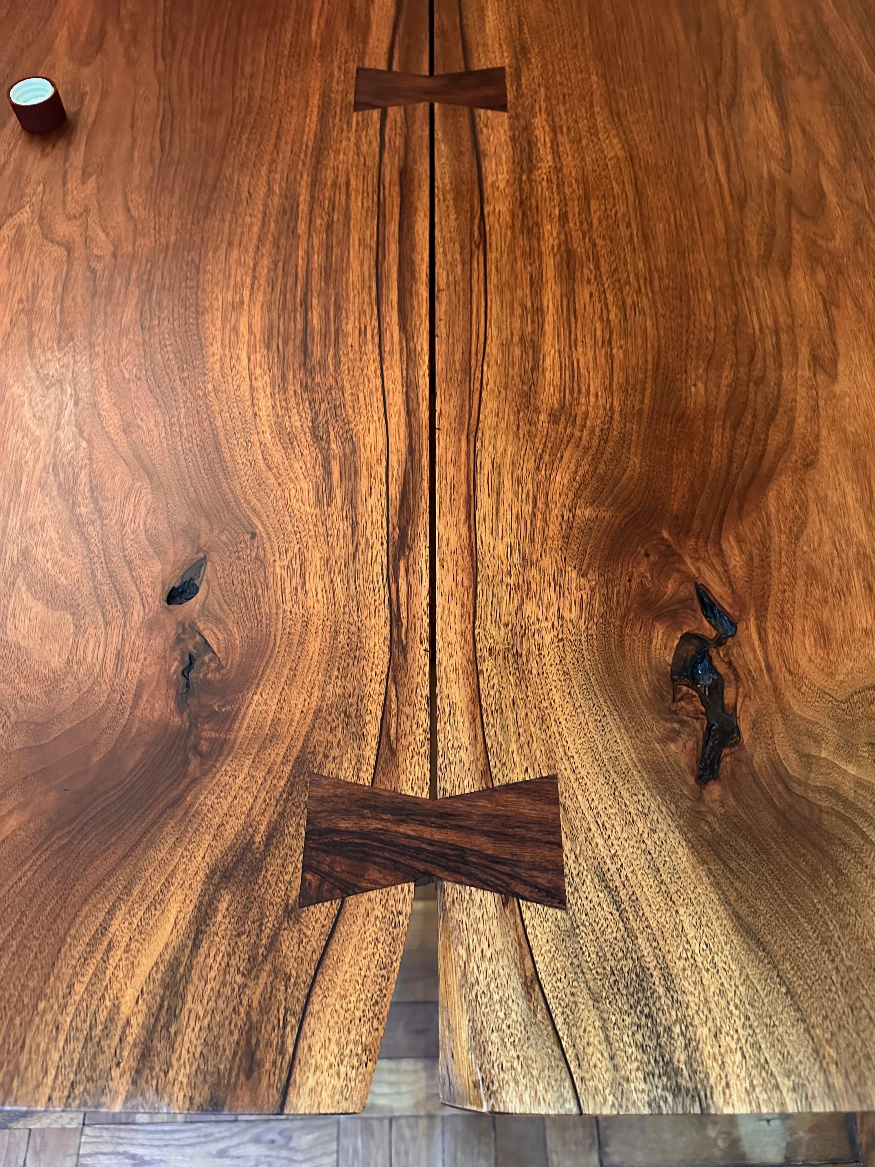 Trestle dining table: this table, built by George Nakashima in 1978, consists of bookmatched solid walnut boards, with five rosewood butterfly joints, The top fits precisely to the base and is secured with pegs (shown in images) The horizontal rail