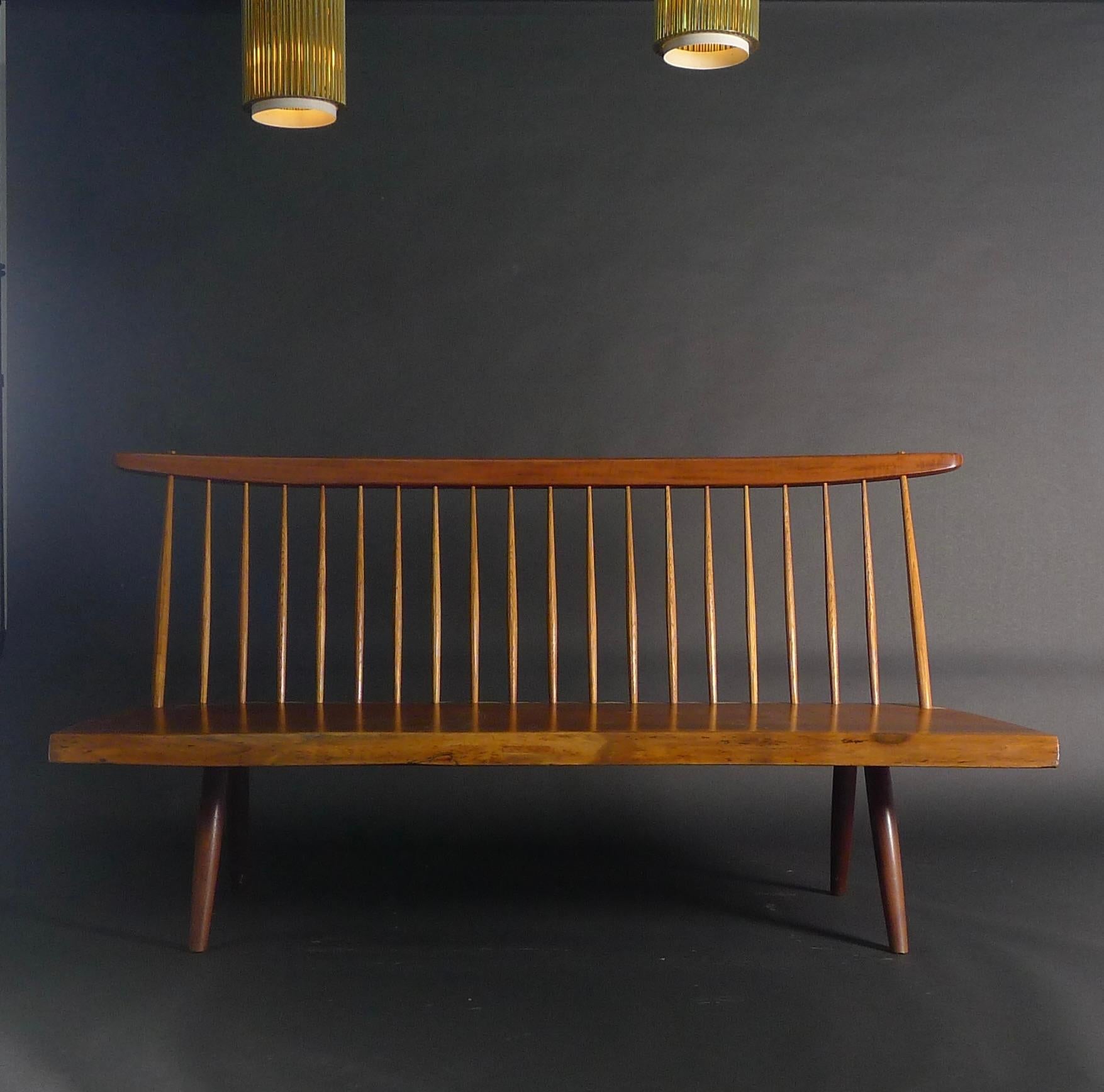 George Nakashima bench, created 1972, carved from a single slab of American black walnut with freeform front edge,  and with turned hickory spindles to the back

82cm high, 158cm wide, 70cm deep, seat height 36cm

with copy of original order card