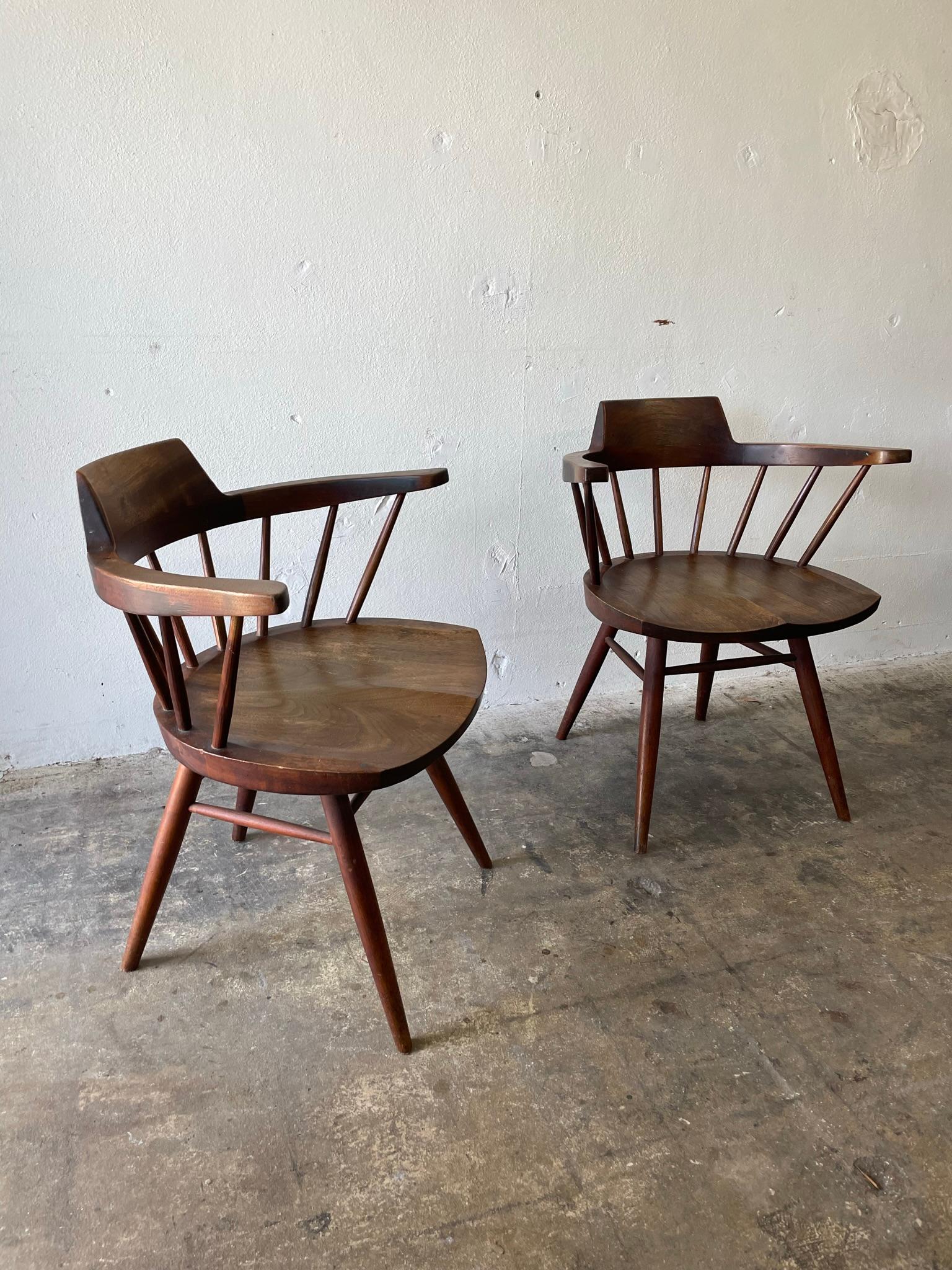 Pair of authentic George Nakashima Captain’s chairs. Walnut. Hand carved seat and spindles. Comes with authenticity receipt from George Nakashima Woodworkers. Originally purchased by a Columbia Records executive in 1960. Original condition, wear and