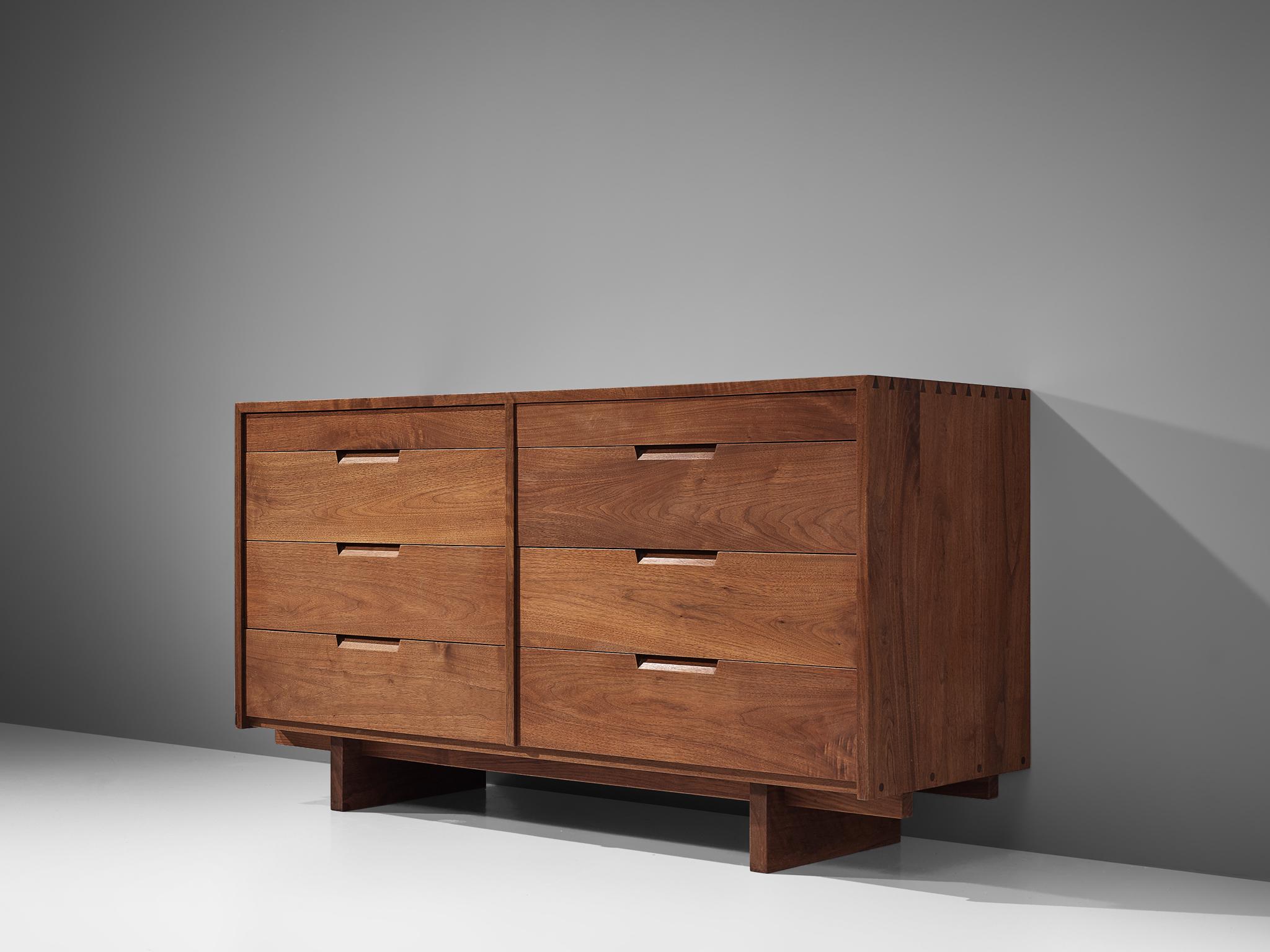 George Nakashima, cabinet in walnut, New Hope, PA, 1963.

This sideboard features eight drawers, executed in walnut with traditional and finished with archetypical dovetail Nakashima wood-joints. The cabinet rests on two slabs of solid walnut that