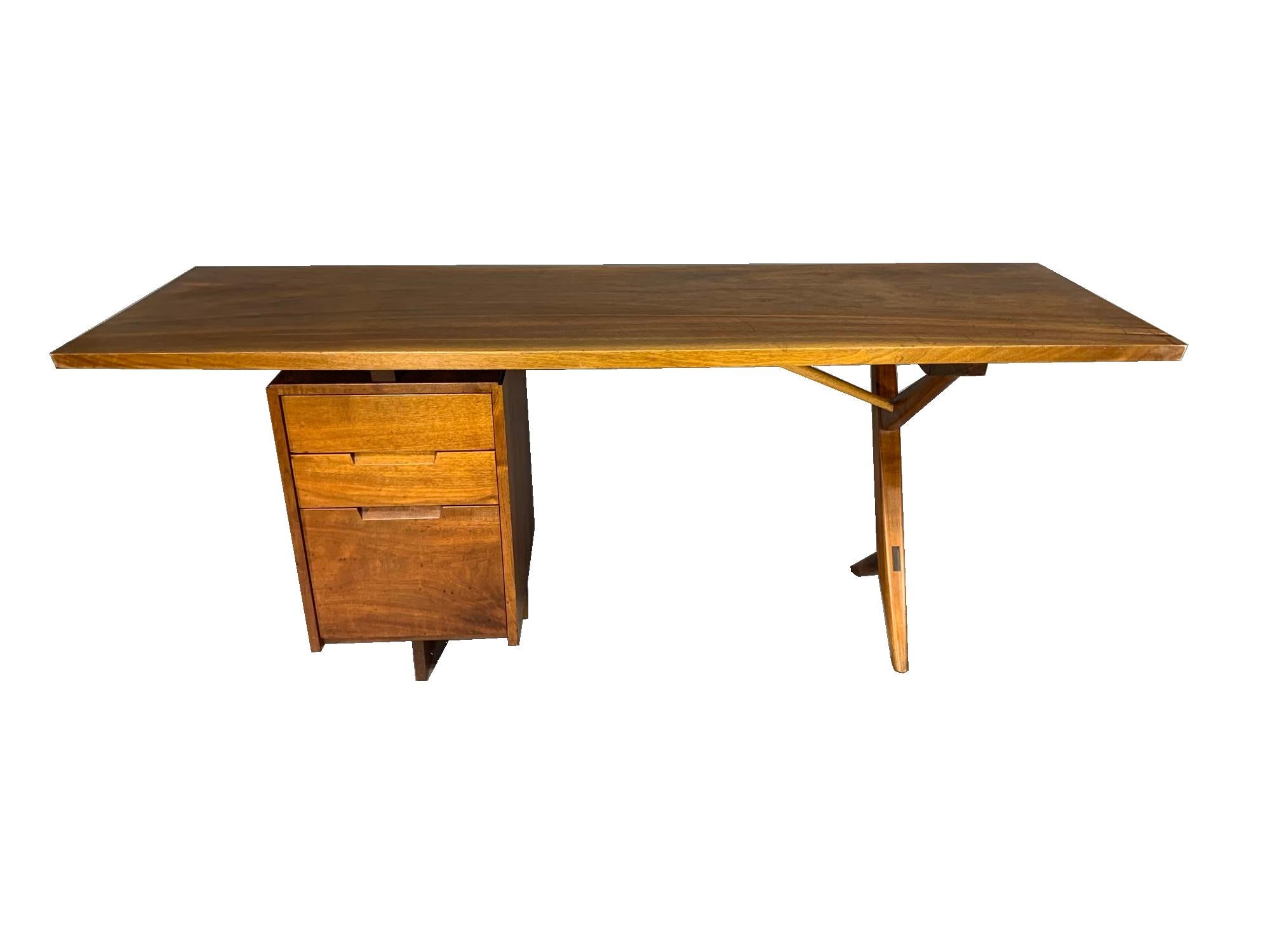 Writing desk circa late 1950s-early 1960s, made by George Nakashima (1905-1990), New Hope, Pennsylvania, American black walnut and hickory, “Conoid” style, having plank top with slight serpentine finished edge; with three-drawer pedestal to one end,