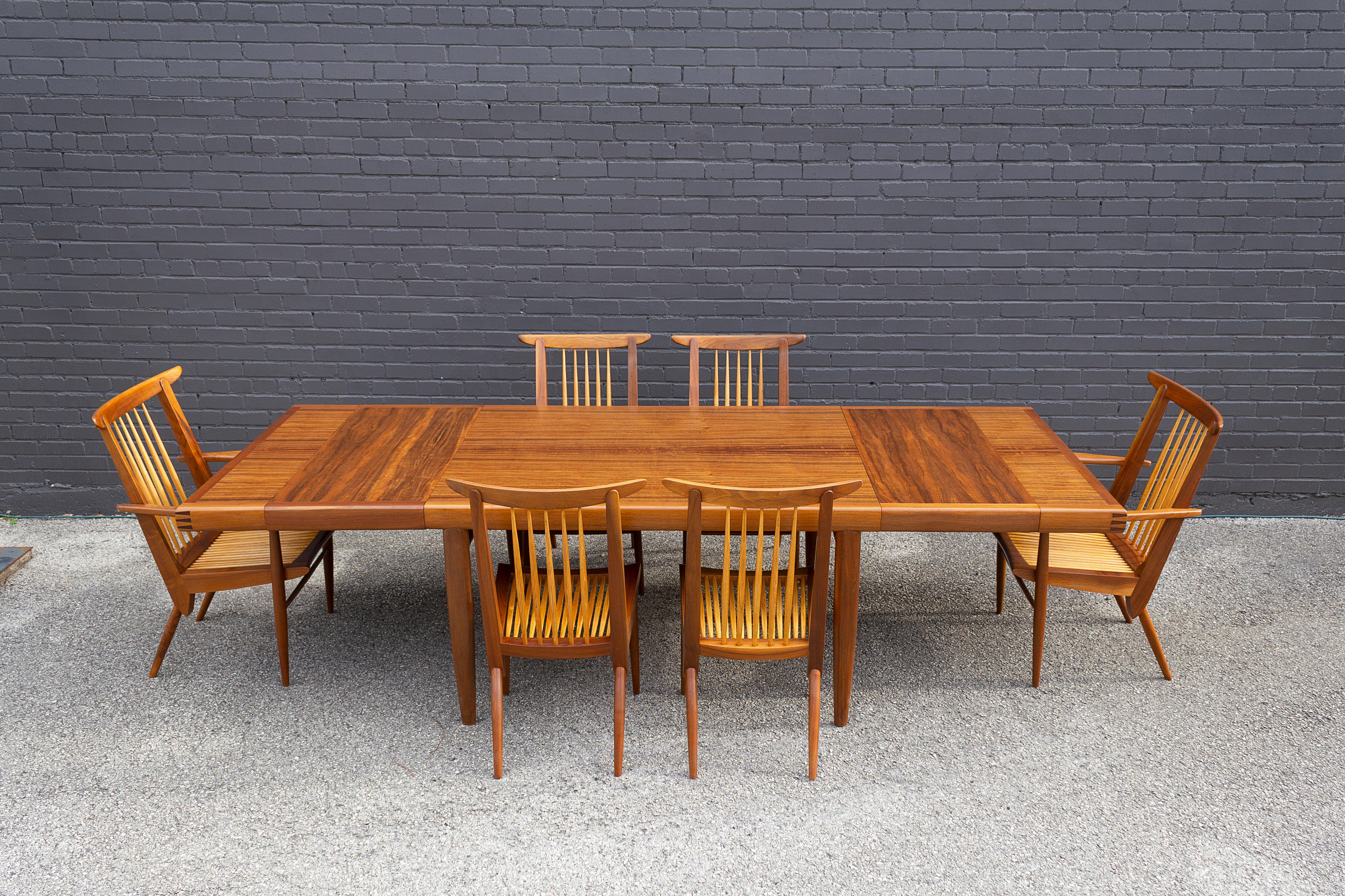 This is a rare and complete George Nakashima Origins Collection dining room set.
The set includes two #259w armchairs, four #259w side chairs, the model #203 dining table, and two matching extensions. The table retains the original Widdicomb label