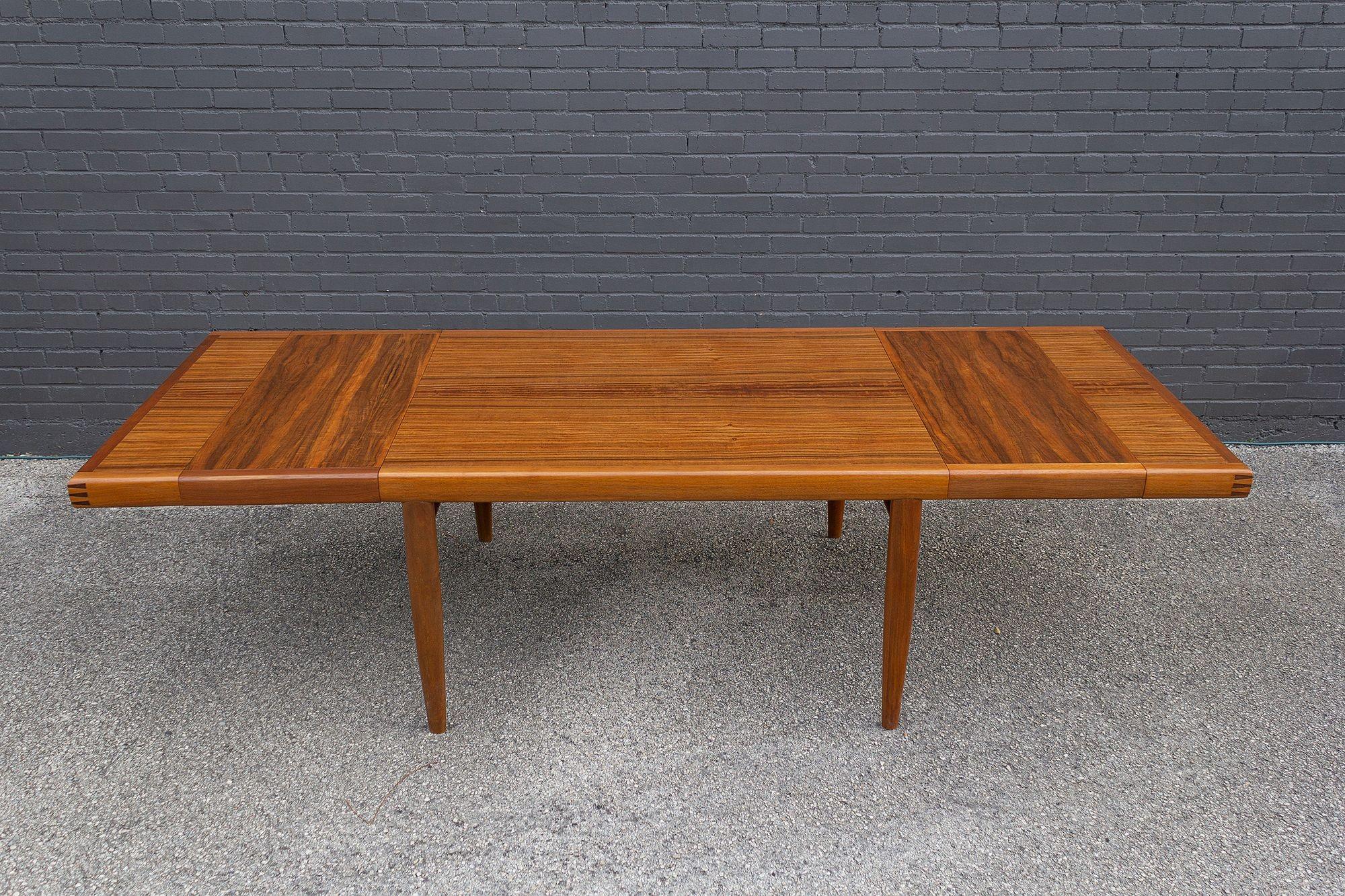 This is a rare and complete George Nakashima Origins Collection dining room table. This piece is model #203 and includes the two matching extensions. The table retains the original Widdicomb label in the center and one of the leaves is branded with