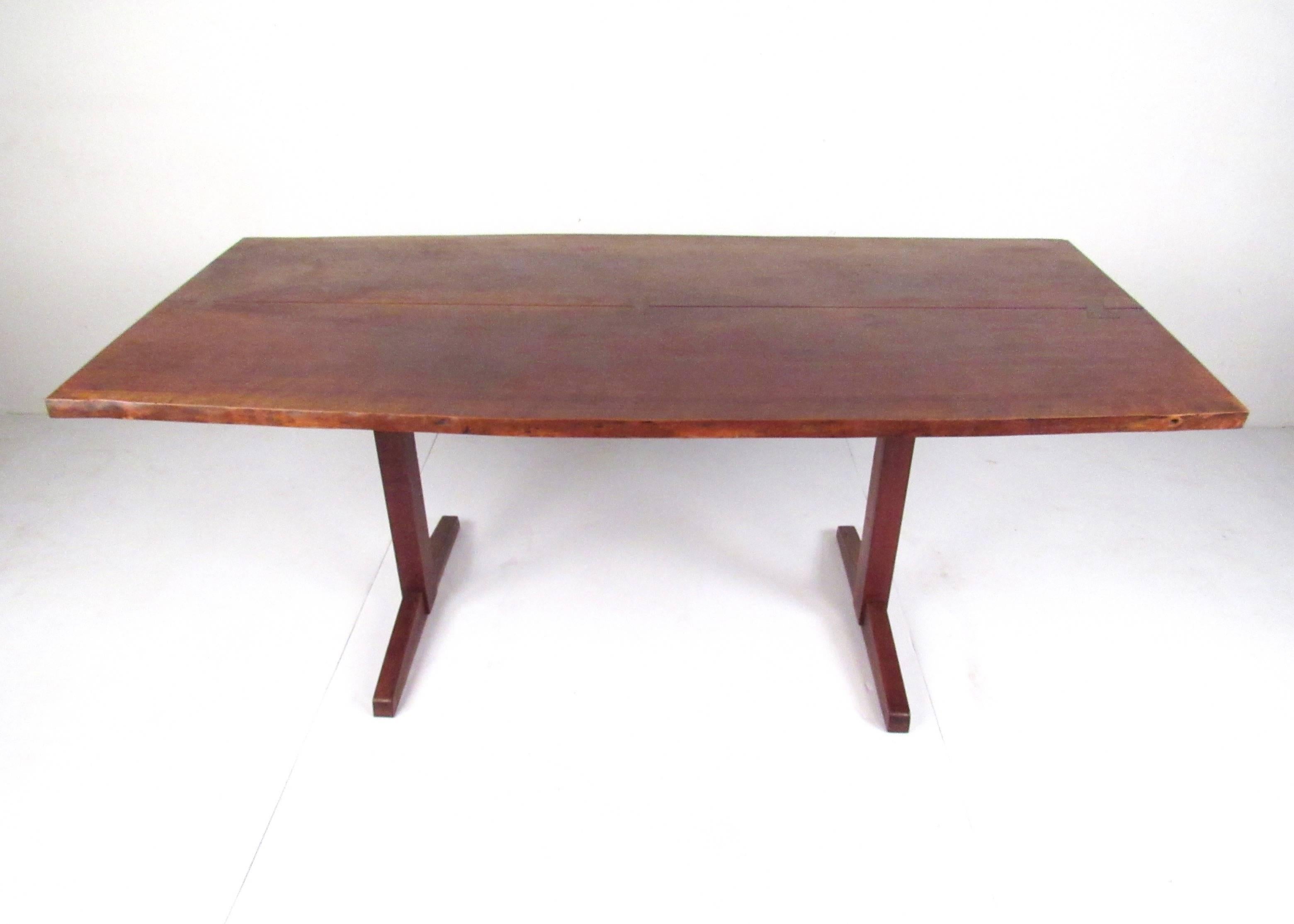 This vintage walnut dining table by George Nakashima features free-flowing live-edge design complete with iconic bowtie inlay. This trestle dining table is constructed from quality midcentury walnut and makes an impressive addition to any Modern