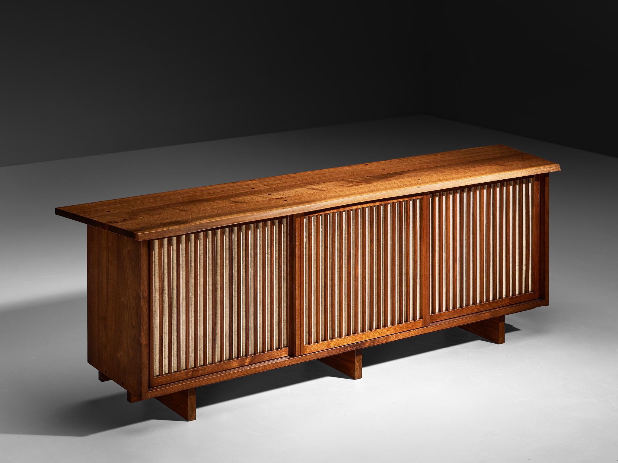 George Nakashima, sideboard, walnut, pandanus cloth, United States, 1963. 

With regard to its essential form, material use, and woodwork, this triple sliding-door sideboard is a testimony to George Nakashima's expert craftsmanship and distinctive