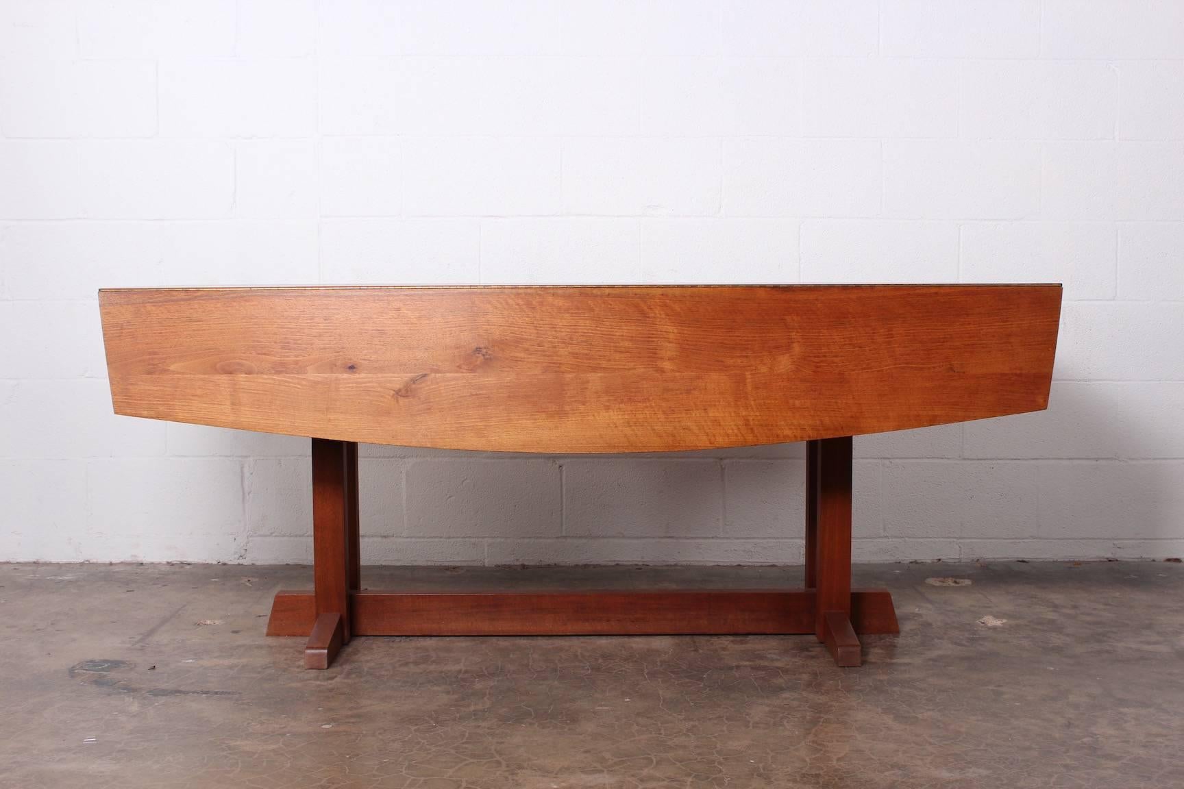 A rare form. Walnut drop-leaf dining / console table with Frenchman's cove base, 1967. Sold with a copy of the original invoice.
Measures: 72.25 x 28.5 x 24.5 W (closed) 48.25 W (open).