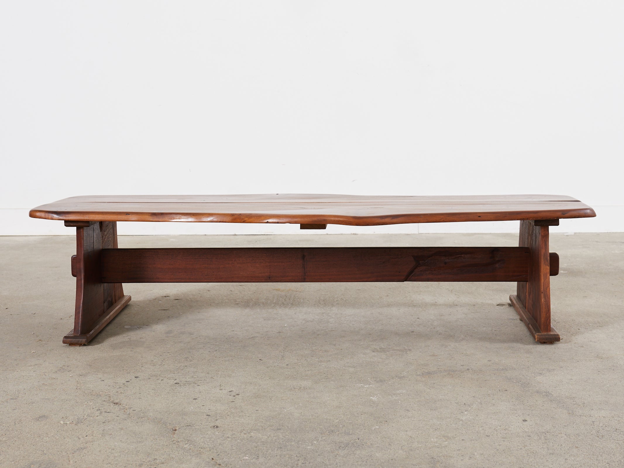 Organic walnut bench coffee table inspired by George Nakashima constructed from two thick slabs of walnut. Featuring a natural edge and supported by a trestle style base with an exposed mortise and tenon joinery. This bench could also serve as a