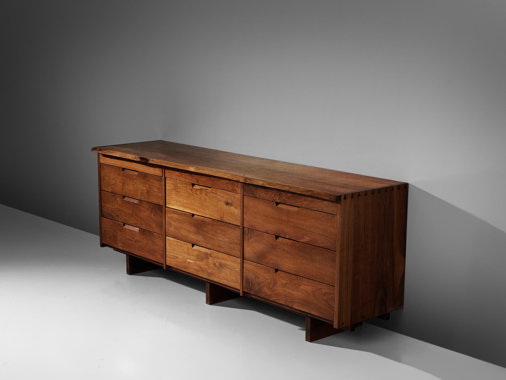 George Nakashima, cabinet in walnut, New Hope, PA, 1960s-1970s.

This cabinet features nine drawers, executed in walnut with traditional and finished with archetypical dovetail Nakashima wood-joints. The large dresser rests on three slabs of solid