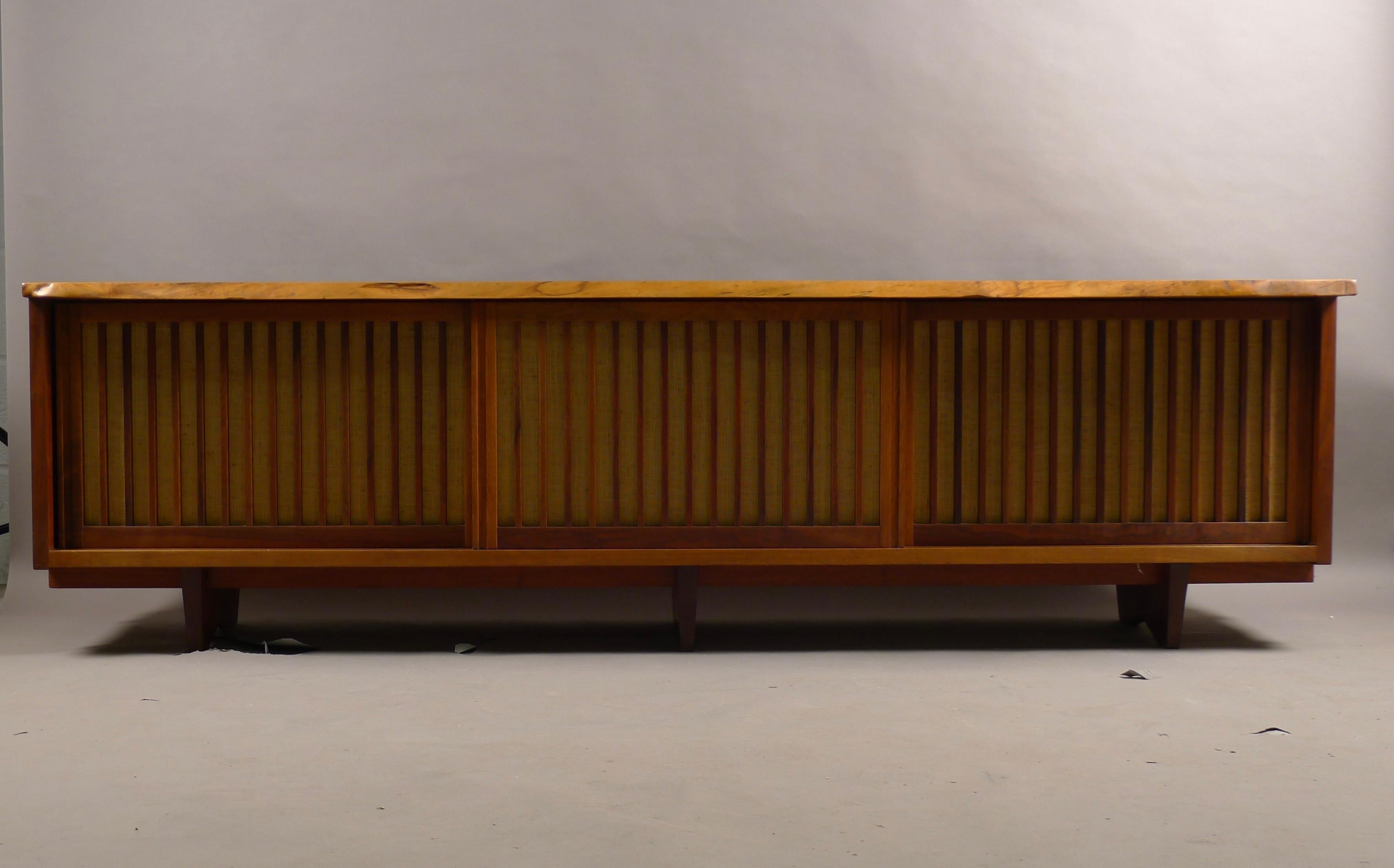 George Nakashima exceptional room divider or credenza, can function in either role as the cabinet is also finished on the back with solid timber. Constructed from Persian Walnut with a freeform overhanging top above three sliding doors which retain