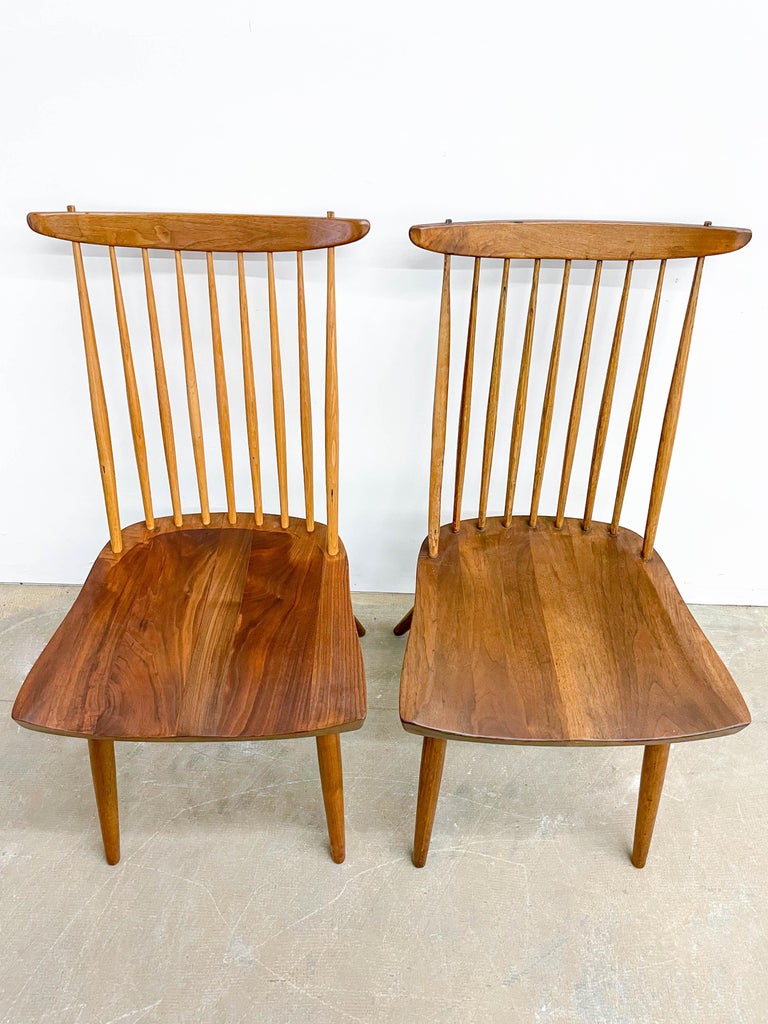 Pair of chairs designed by George Nakashima and made by Widddicomb in the late 1950s as part of their ‘Origins’ line. Known as ‘New’ chairs, these have solid walnut seats and legs, with a seat back of hickory spindles topped by dramatic crescents of