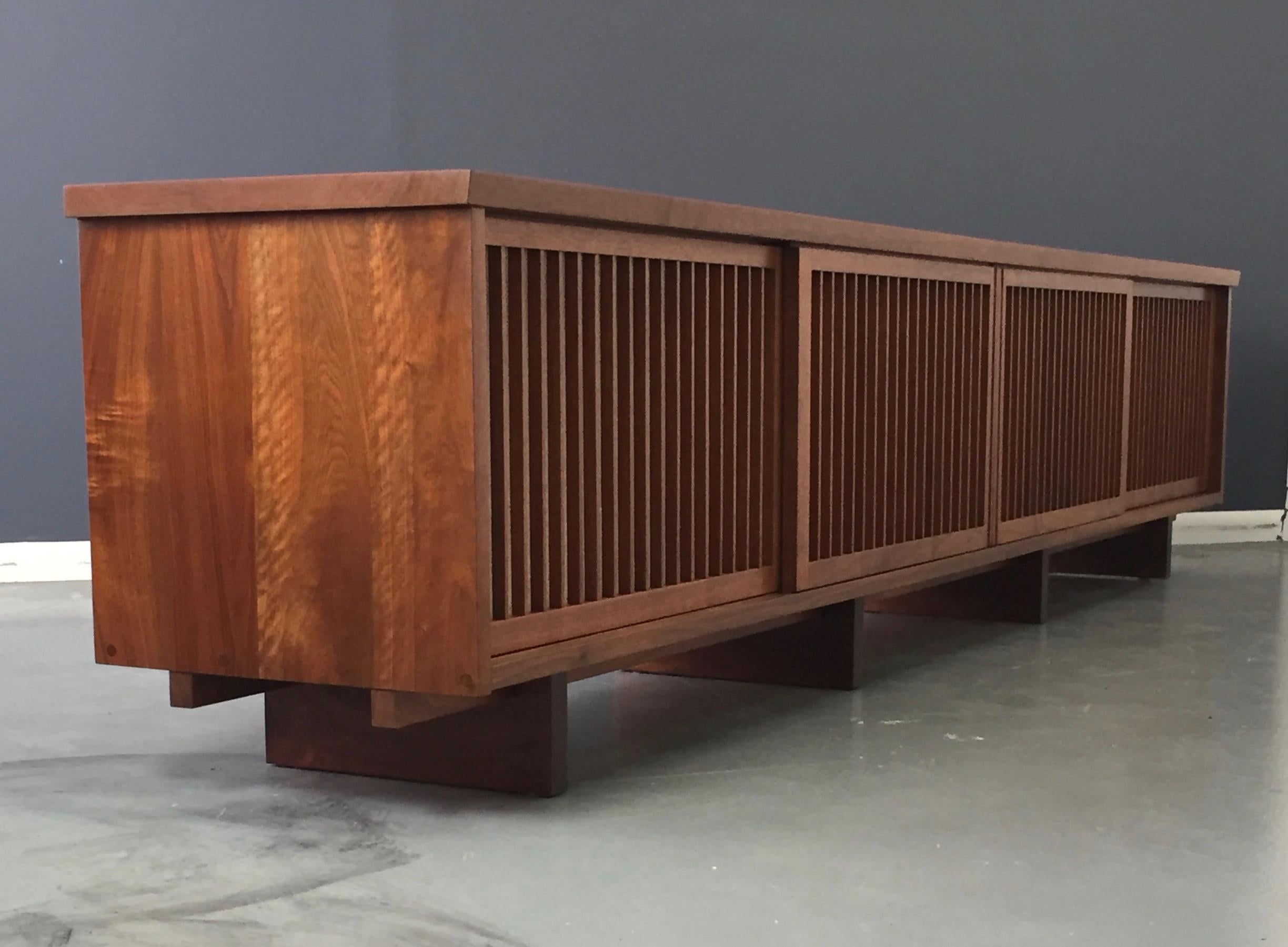 Mrs. J Faust commissioned George Nakashima in 1957 to produce this massive four sliding door credenza in walnut with a teak top for her home in Bala Cynwyd Pennsylvania. The description of the credenza is evidenced by the 