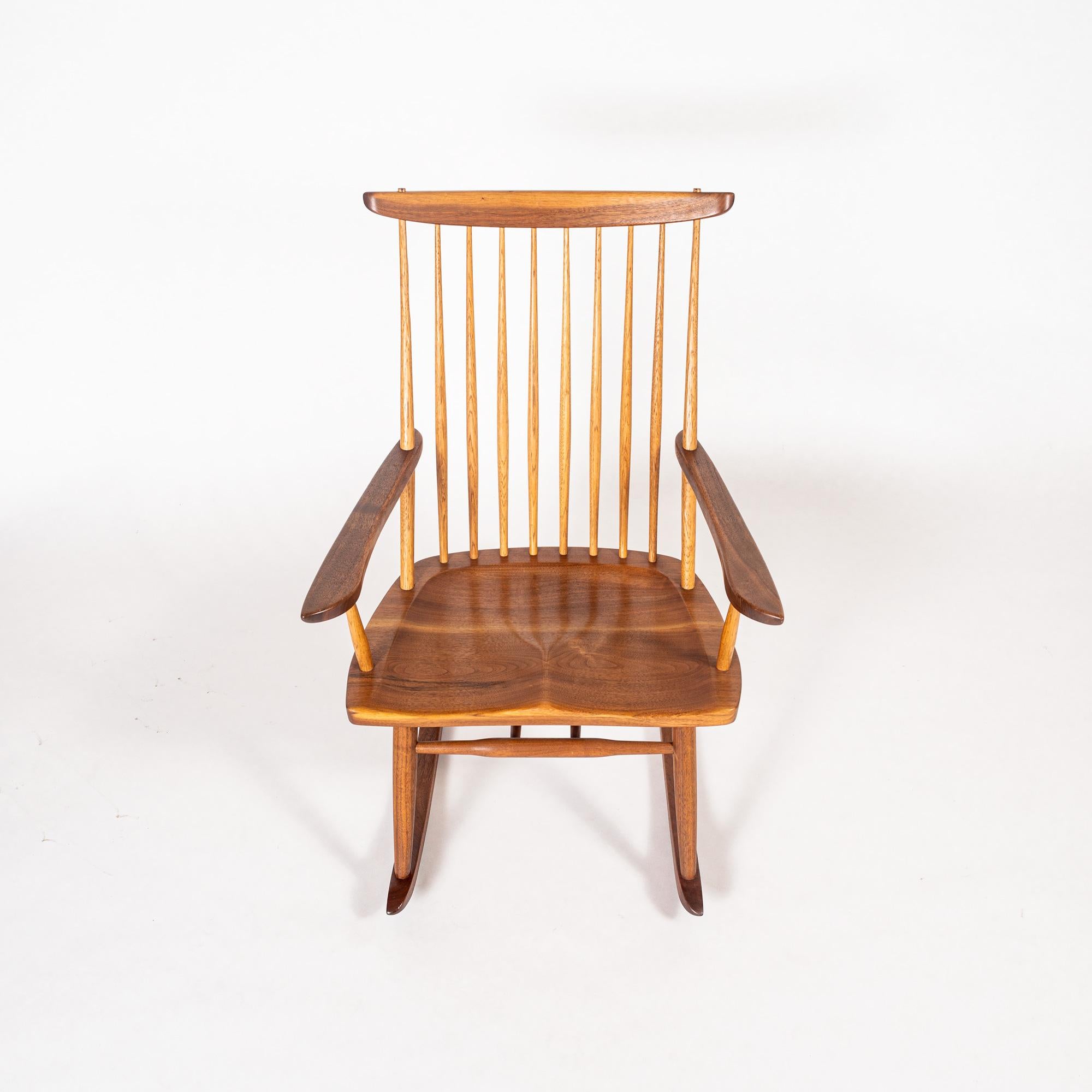 A pair of rocker in walnut with hickory spindles and sculpted arms by George Nakashima, circa 1970s. Client name marked on underside. A Washington State native, master woodworker and M.I.T.-trained architect, George Nakashima was the leading light