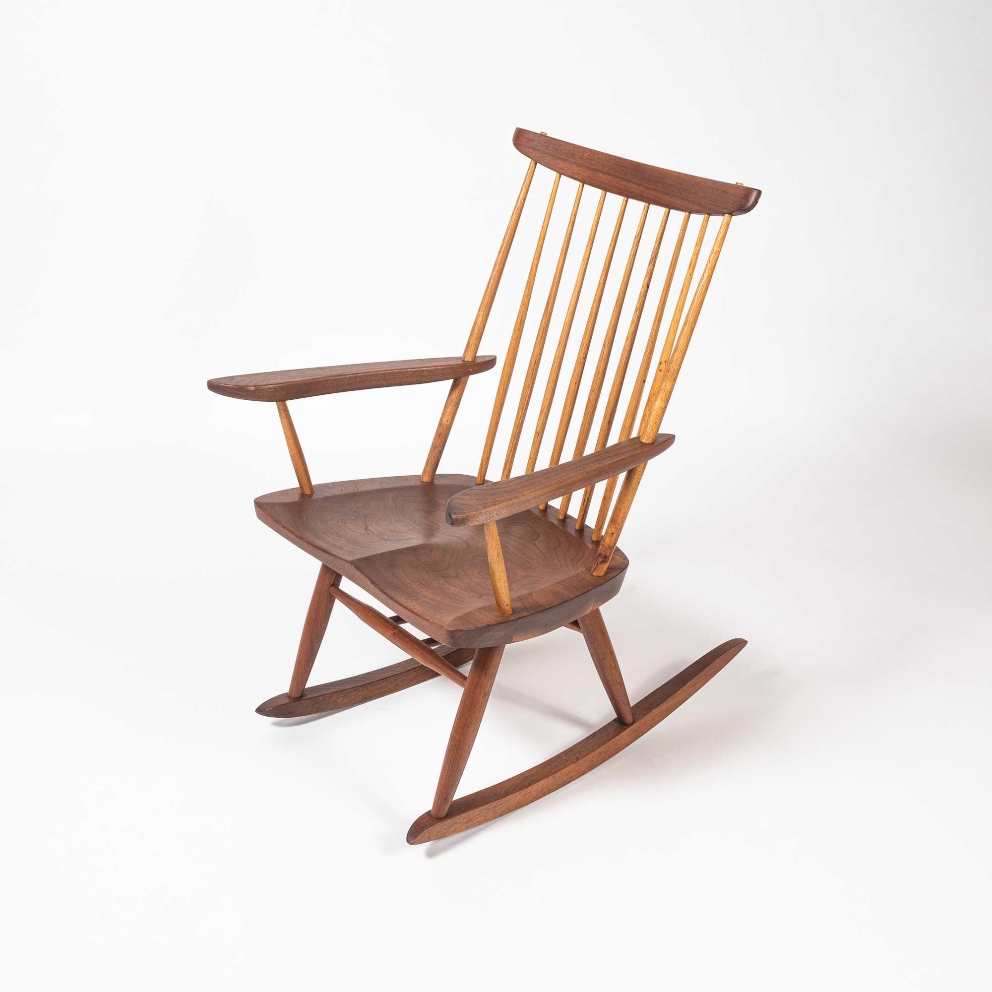 Rocker in walnut with hickory spindles and sculpted arms by George Nakashima, circa 1994. Signature on the bottom of the chair. A Washington State native, master woodworker and M.I.T.-trained architect, George Nakashima was the leading light of the