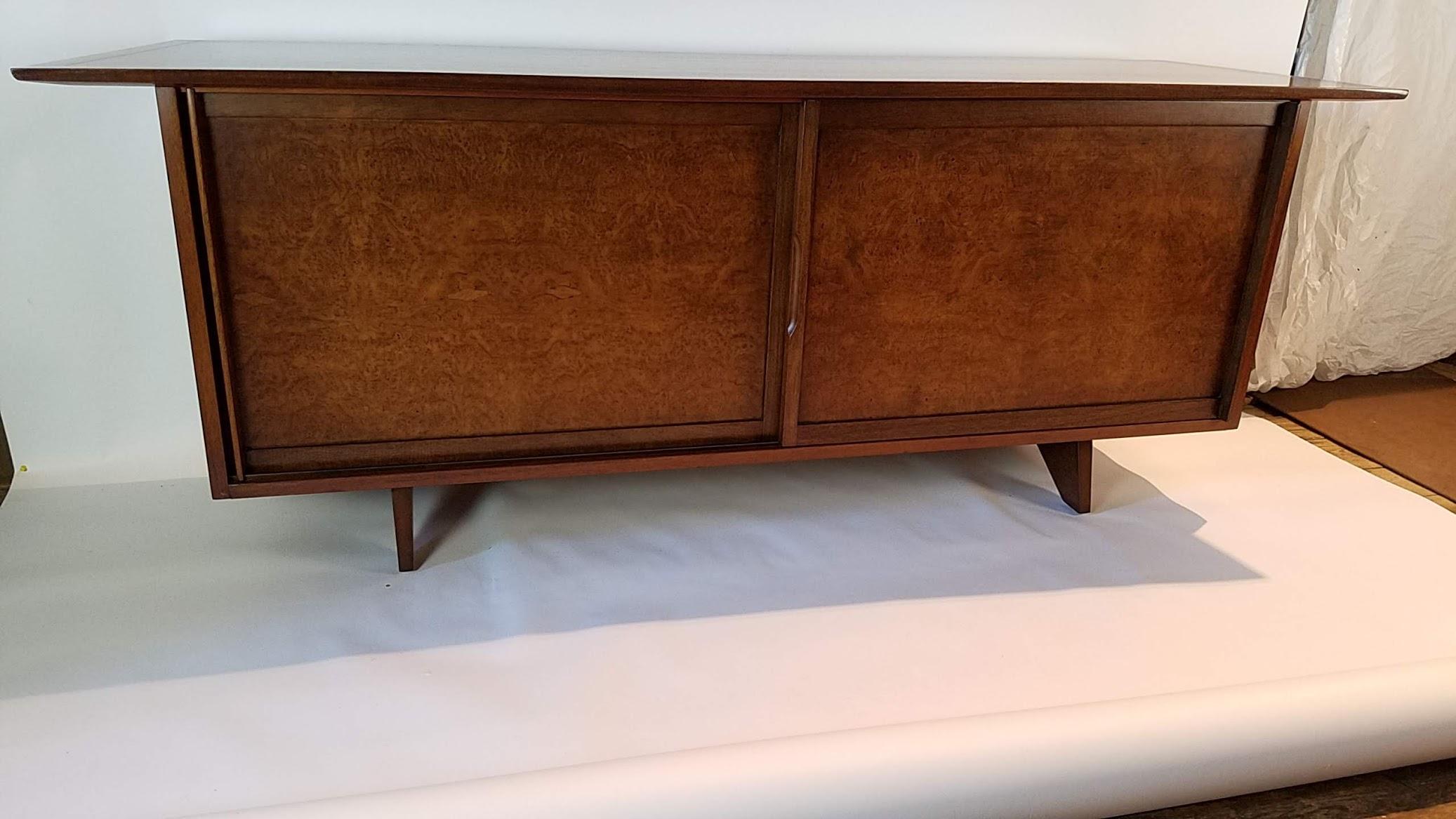 George Nakashima sideboard designed as part of his origins line of furniture for the Widdicomb Furniture Company. Beautifully detailed as one expects from this master furniture creator. A reverse bow top overhangs two maple burl paneled