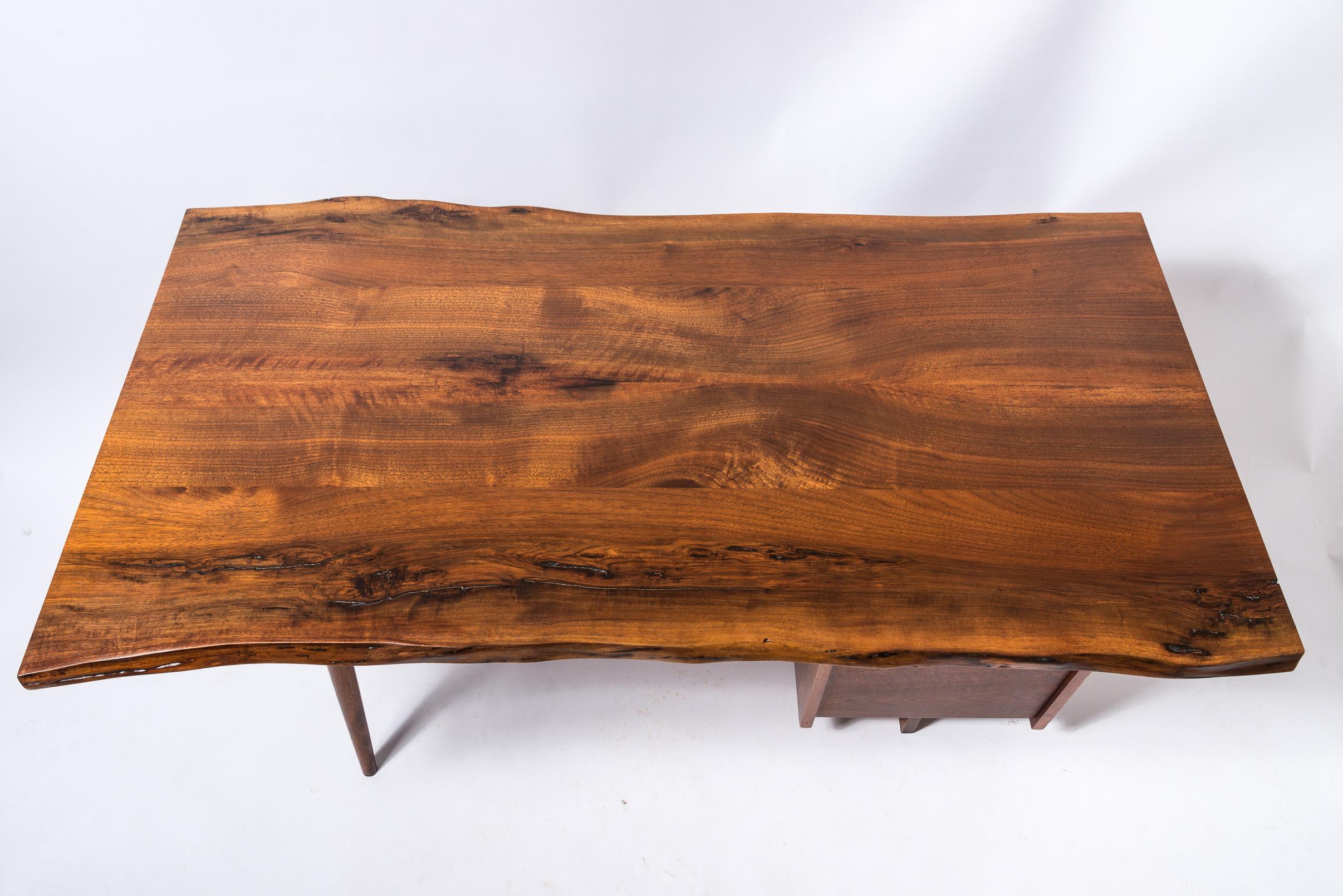 Bureau à piédestal unique de George Nakashima
Bureau à pieds évasés en noyer
Caisson 3 tiroirs
Signé sous le bureau, George Nakashima 1968
Nom du client original marqué au crayon dans les tiroirs
Plateau à grains expressifs comprenant de multiples