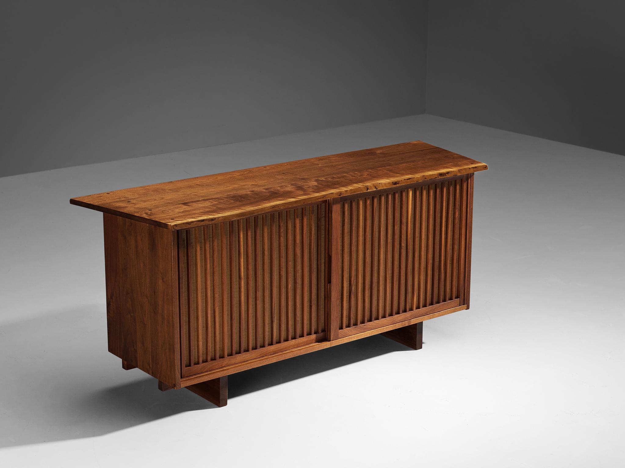 George Nakashima, cabinet, walnut, pandanus cloth, United States, 1966. 

With regard to its essential form, material use, and woodwork, this two-door sliding-door sideboard is a testimony to George Nakashima's expert craftsmanship and distinctive