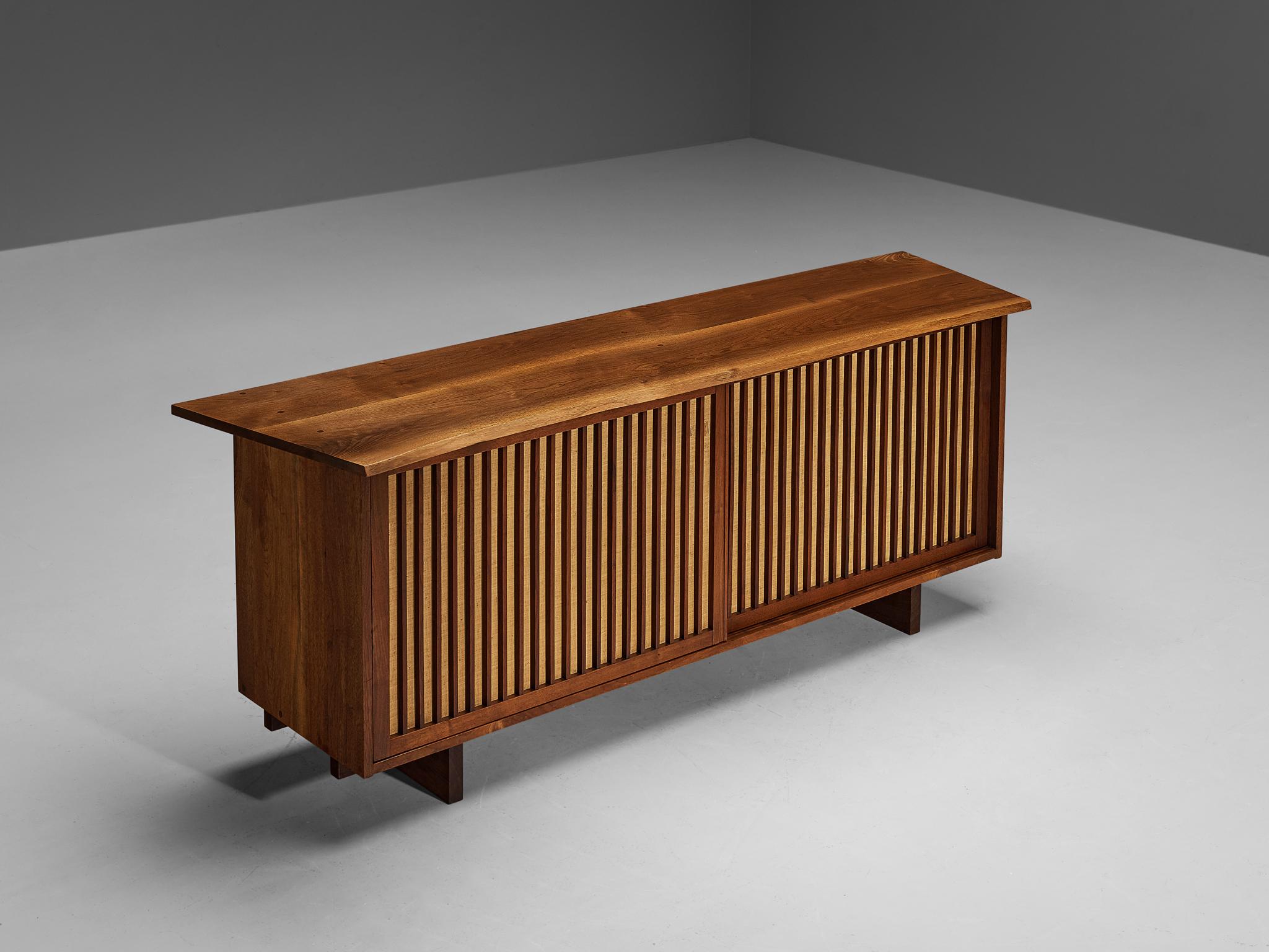 George Nakashima, cabinet, noyer, tissu de pandanus, États-Unis, 1962. 

En ce qui concerne sa forme essentielle, l'utilisation des matériaux et le travail du bois, ce buffet à deux portes coulissantes témoigne de l'expertise artisanale et de la