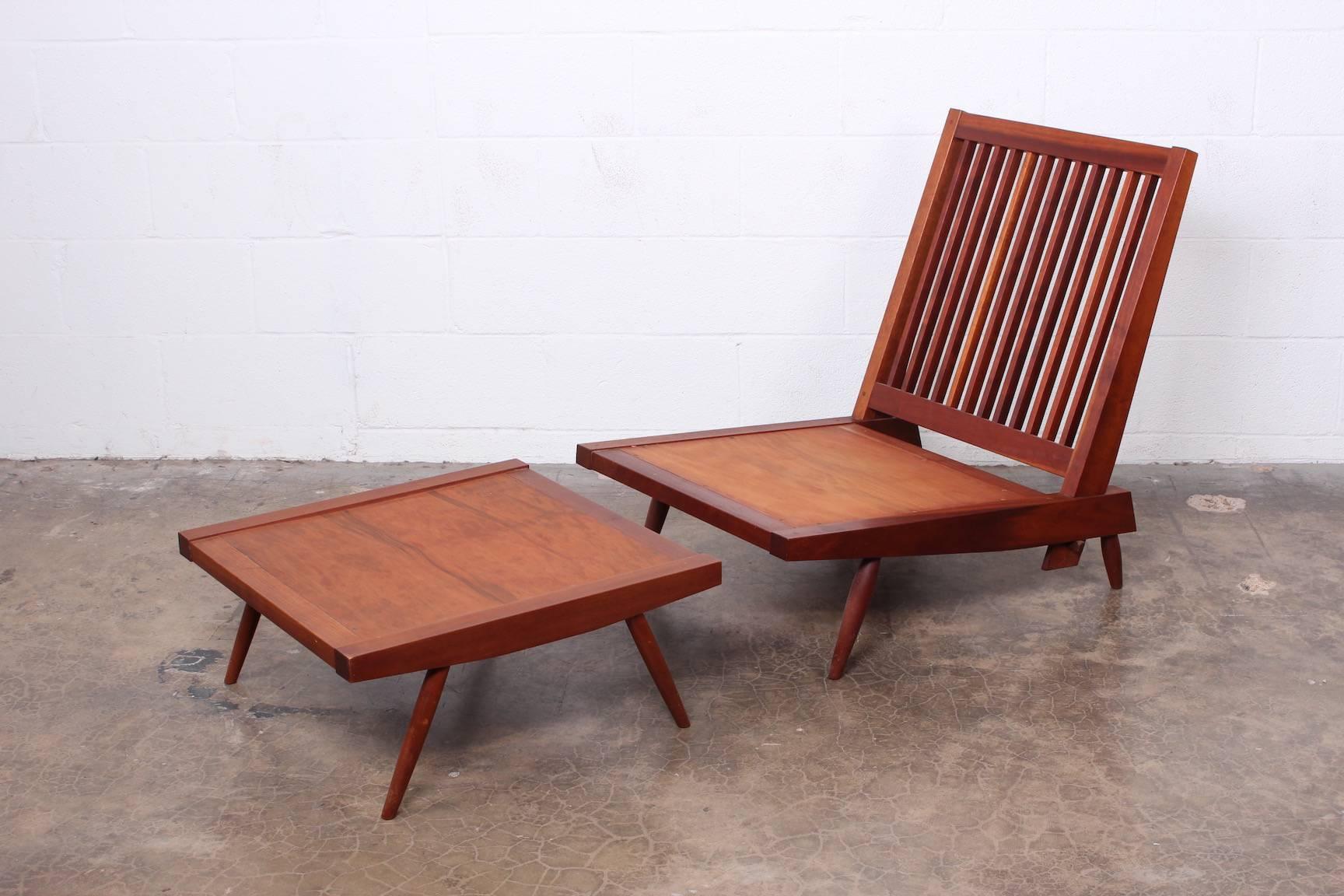 An early spindle back lounge chair and ottoman in cherry in all original condition with original fabric. Fully documented with copy of receipt from 1952.