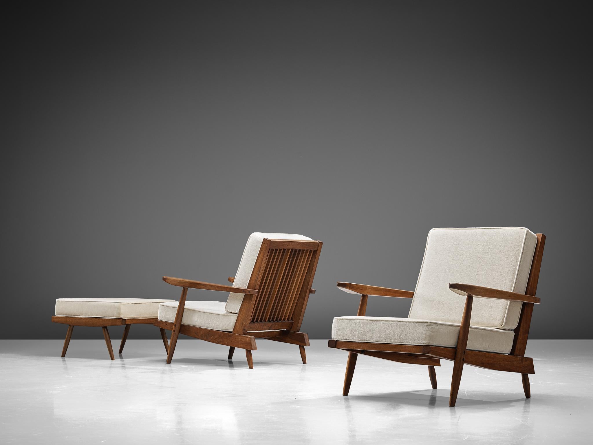 George Nakashima, armchairs, walnut, ivory fabric, United States, design, circa 1950.  

These quintessential spindleback armchairs and ottomans are designed by Nakashima. The chairs feature spindles at the back, referring with this detail to the