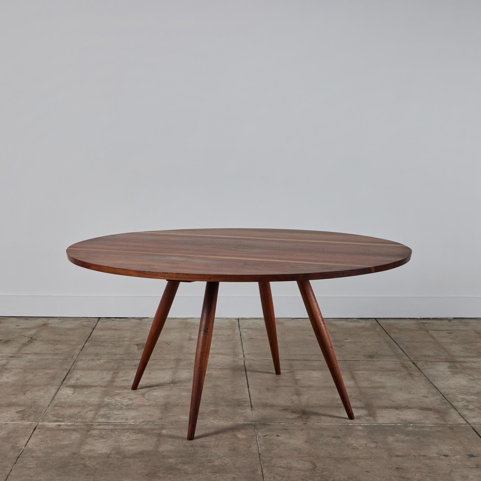 Table de salle à manger de l'artisan américain du milieu du siècle George Nakashima. La table en noyer noir est dotée de quatre pieds en goujon effilés et évasés qui supportent un grand plateau rond. Le plateau de la table présente des dalles de