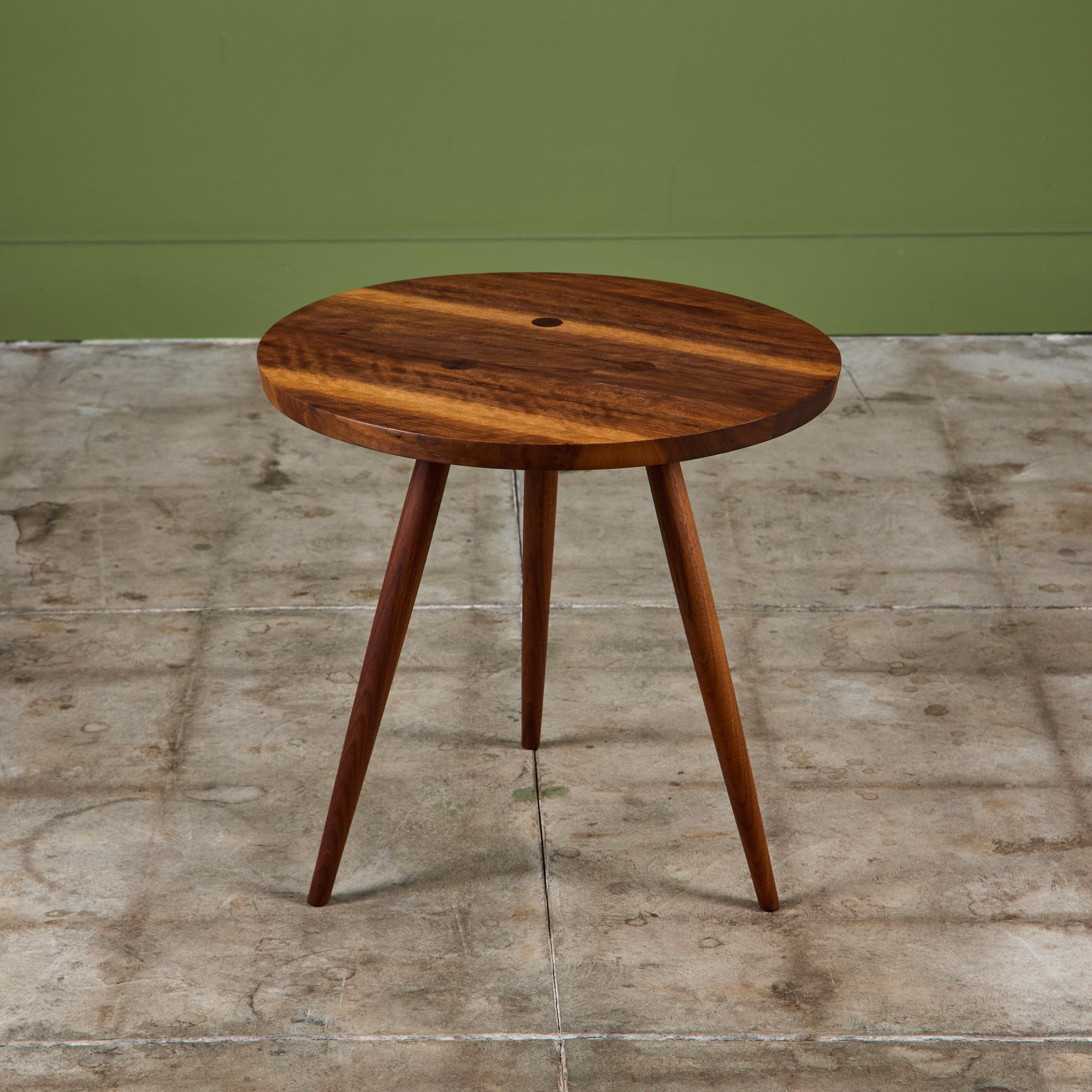 Black walnut side table from the New Hope, Pennsylvania Studio of George Nakashima. The round table is minimal in design and features three long tapered legs.

Dimensions
21