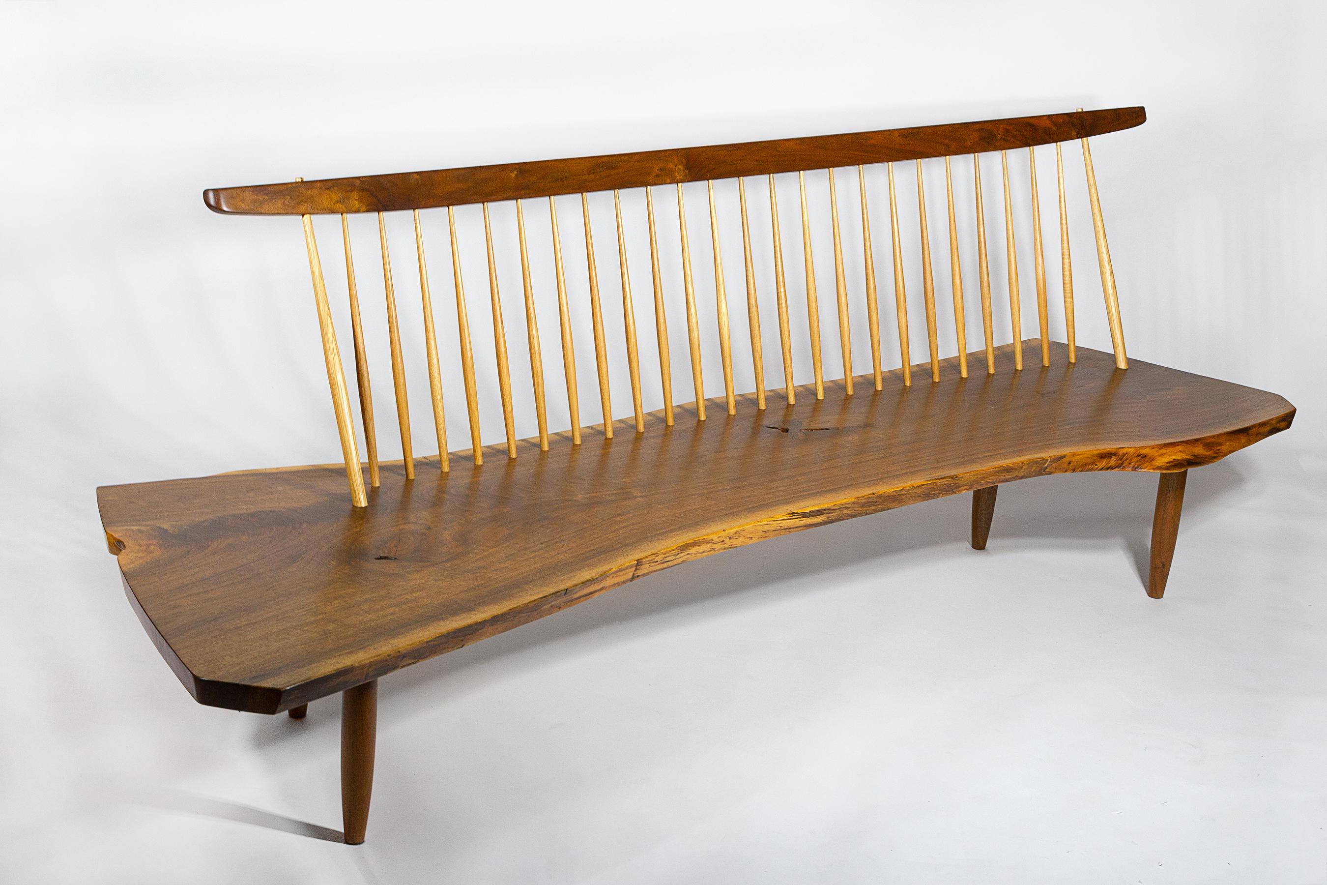 Exquisitely crafted black walnut conoid bench with hand-tooled hickory spindles and a solid rosewood butterfly joint fabricated in the George Nakashima studio by his daughter and protege Mira Nakashima. 
This piece was commissioned for an important