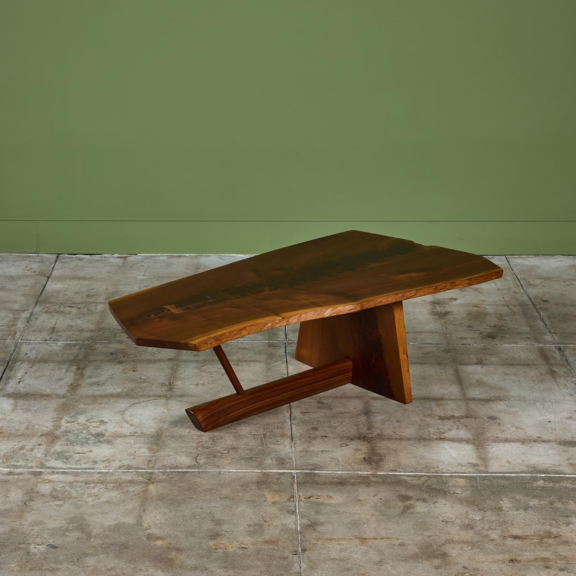 Table basse de l'artisan américain du milieu du siècle George Nakashima. La table en noyer noir, c.C.C., présente un plateau en dalles à bords vifs avec un support en fuseau simple et un support en dalles à bords vifs reliés par un tréteau en noyer.
