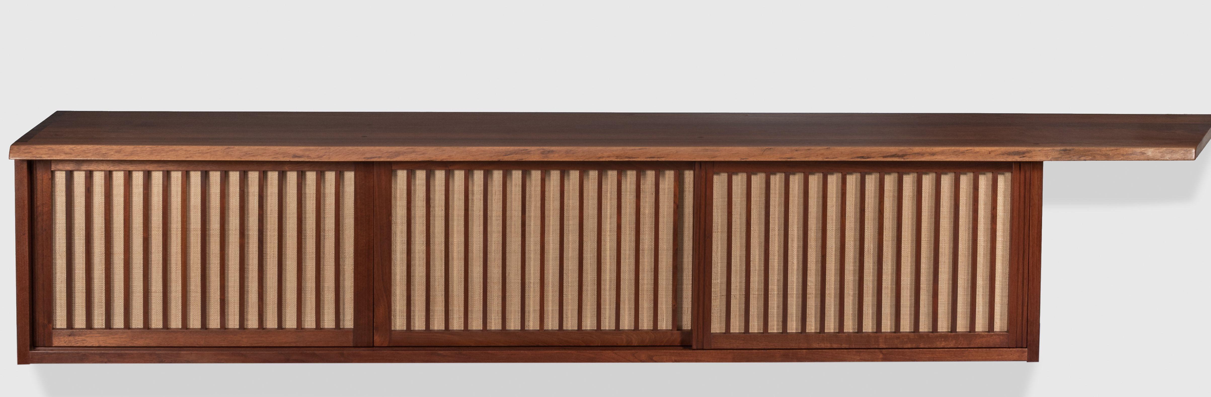 Studio wall-mounted cabinet by woodworker George Nakashima, 1962. Executed in American Black Walnut with Pandanus cloth doors that reveal four drawers and shelves. Provenance and original order card included. Very good original condition. 