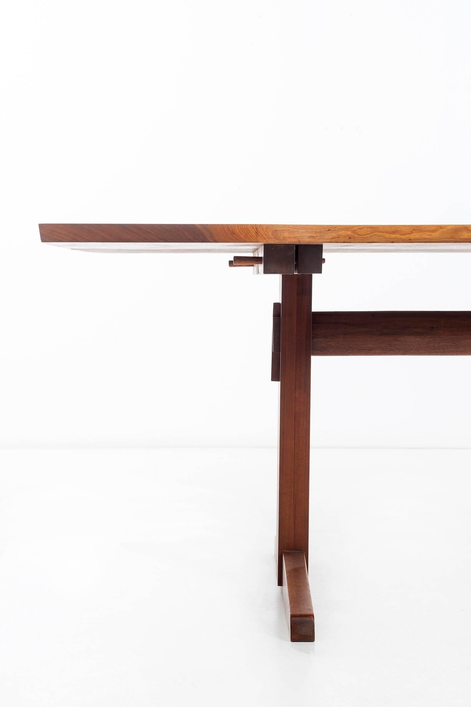 George Nakashima (1905 - 1990)
Custom free-edge American Studio trestle dining table in black walnut with sap grain details. 
The two planks joined and reinforced with rosewood butterflies, fitted precisely to base, 
and secured by walnut pegs.
New