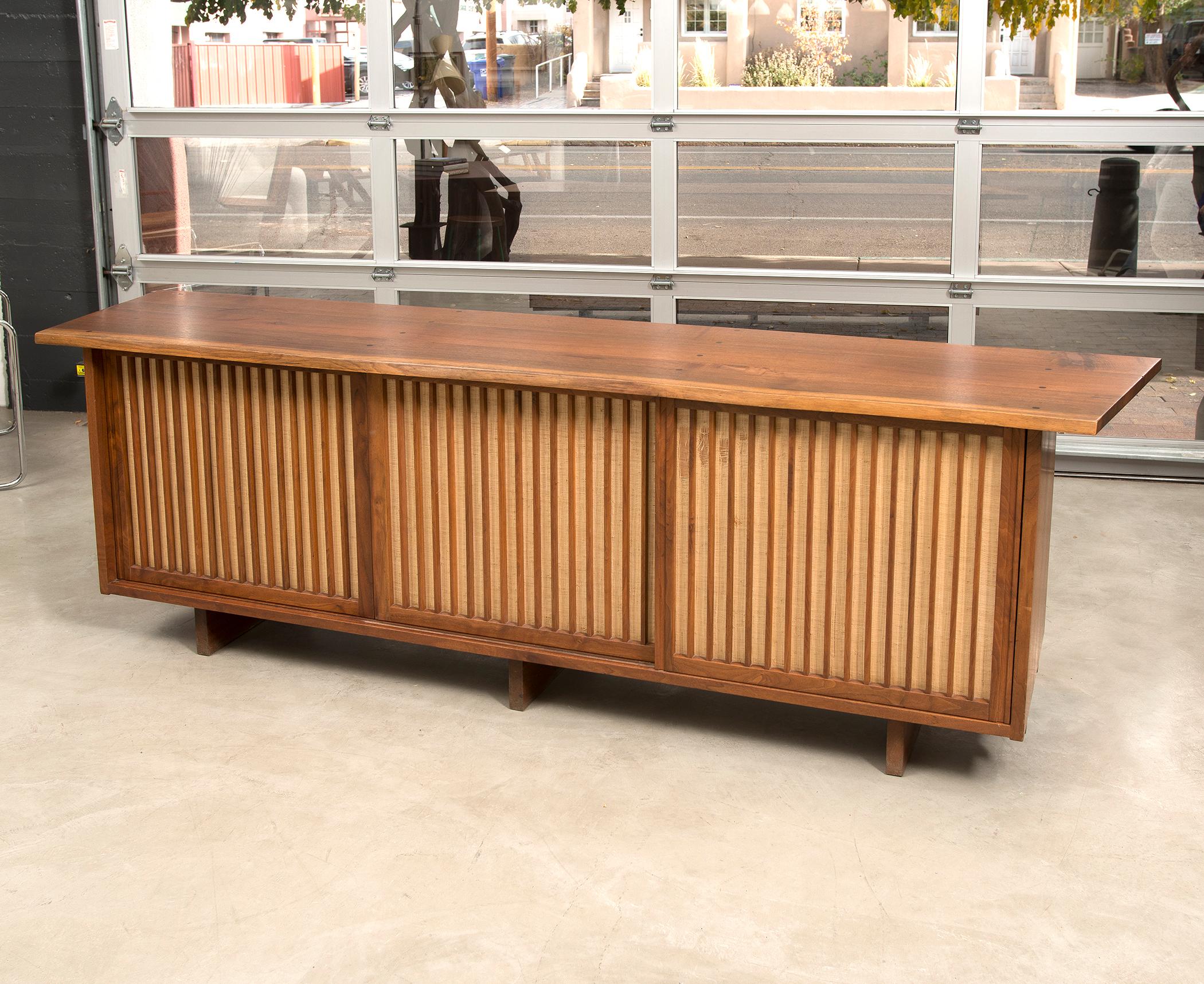 A Classic casepiece by George Nakashima with free edge top, three drawers in the centre, and two shelves on each side. In American black walnut and pandanus cloth, 1968.

The cabinet comes with the original sketch signed and dated by George