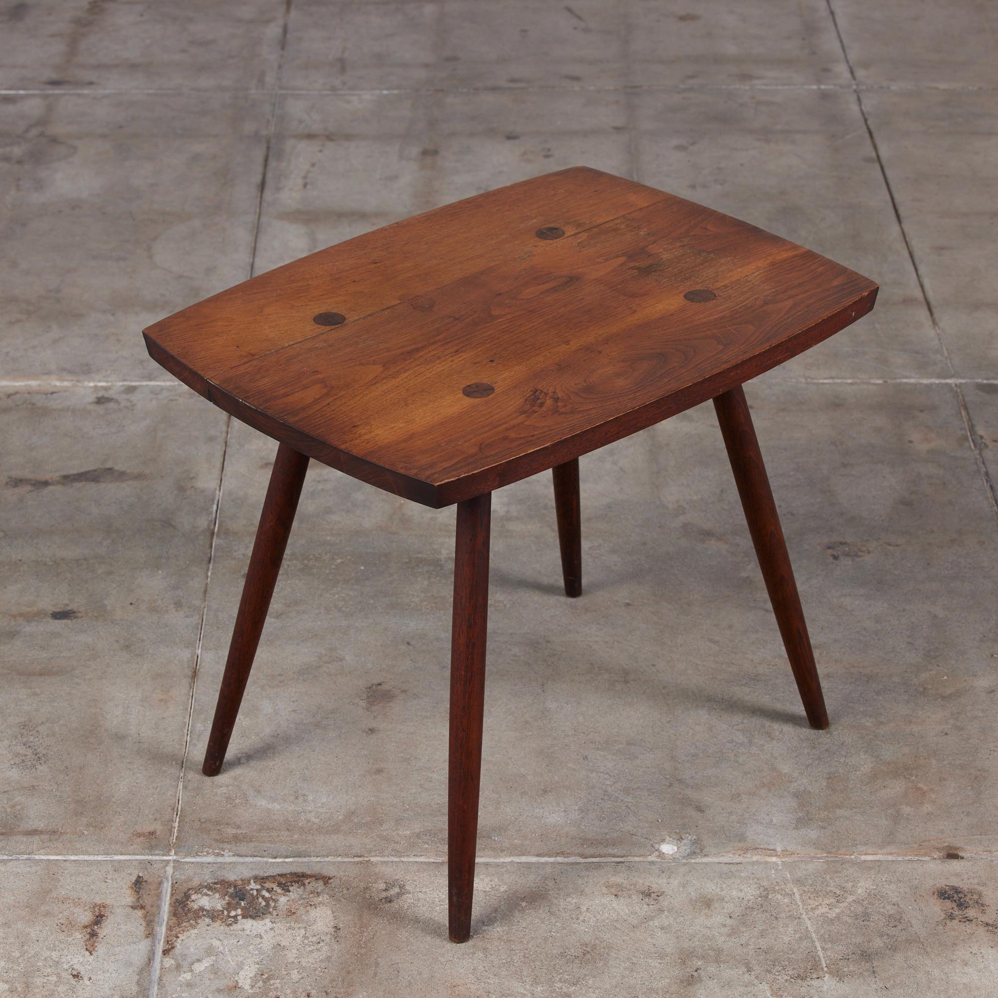 Walnut occasional table from the New Hope, Pennsylvania Studio of George Nakashima. The rectangular table is minimal in design and features long tapered legs.

Dimensions: 24