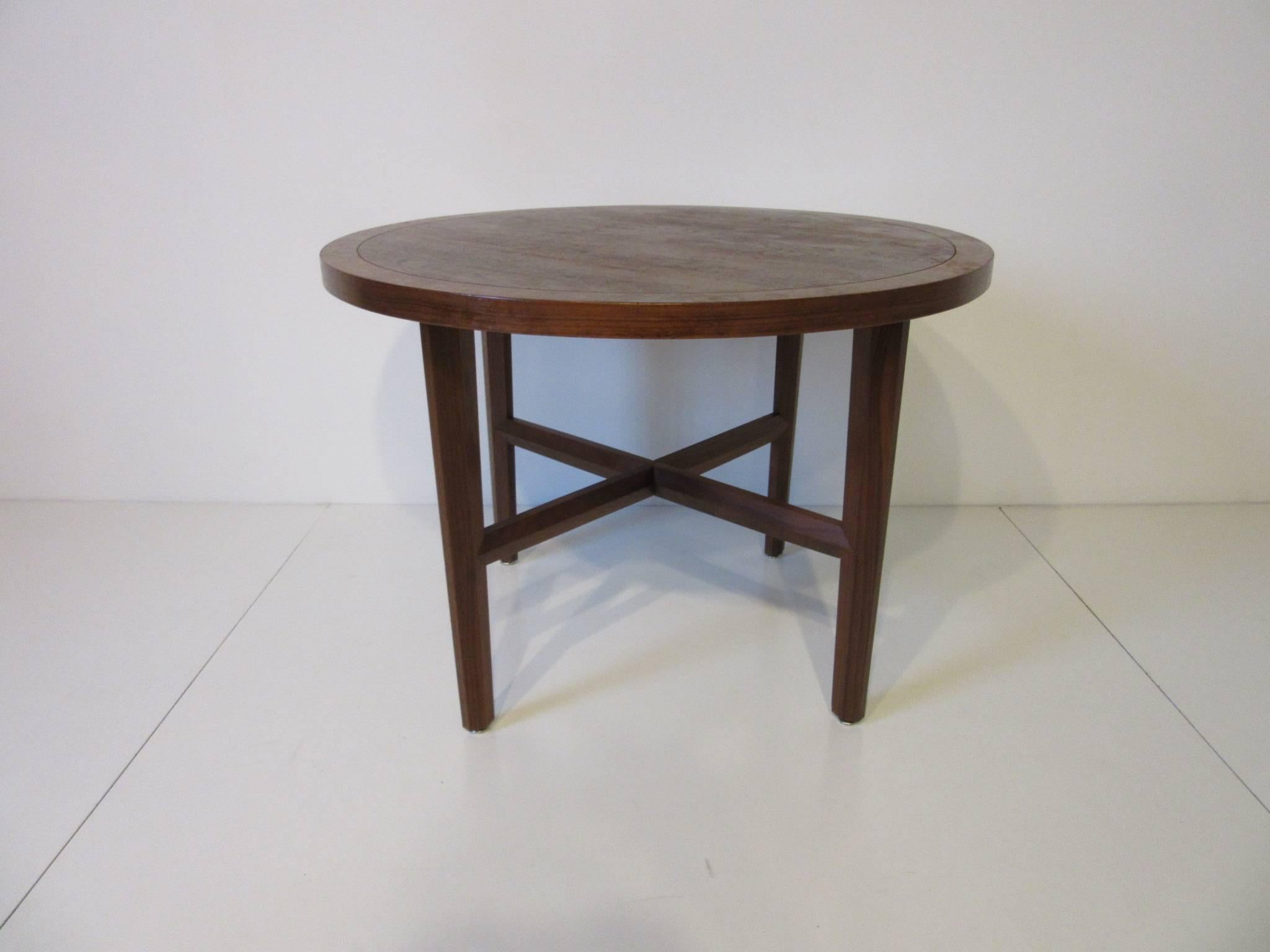 A round Carpathian exotic wood side or lamp table in an oil finish with four tapered and bevelled legs and stretchers designed by George Nakashima. This table comes from Nakashima's only mass produced furniture line named the origins collection by