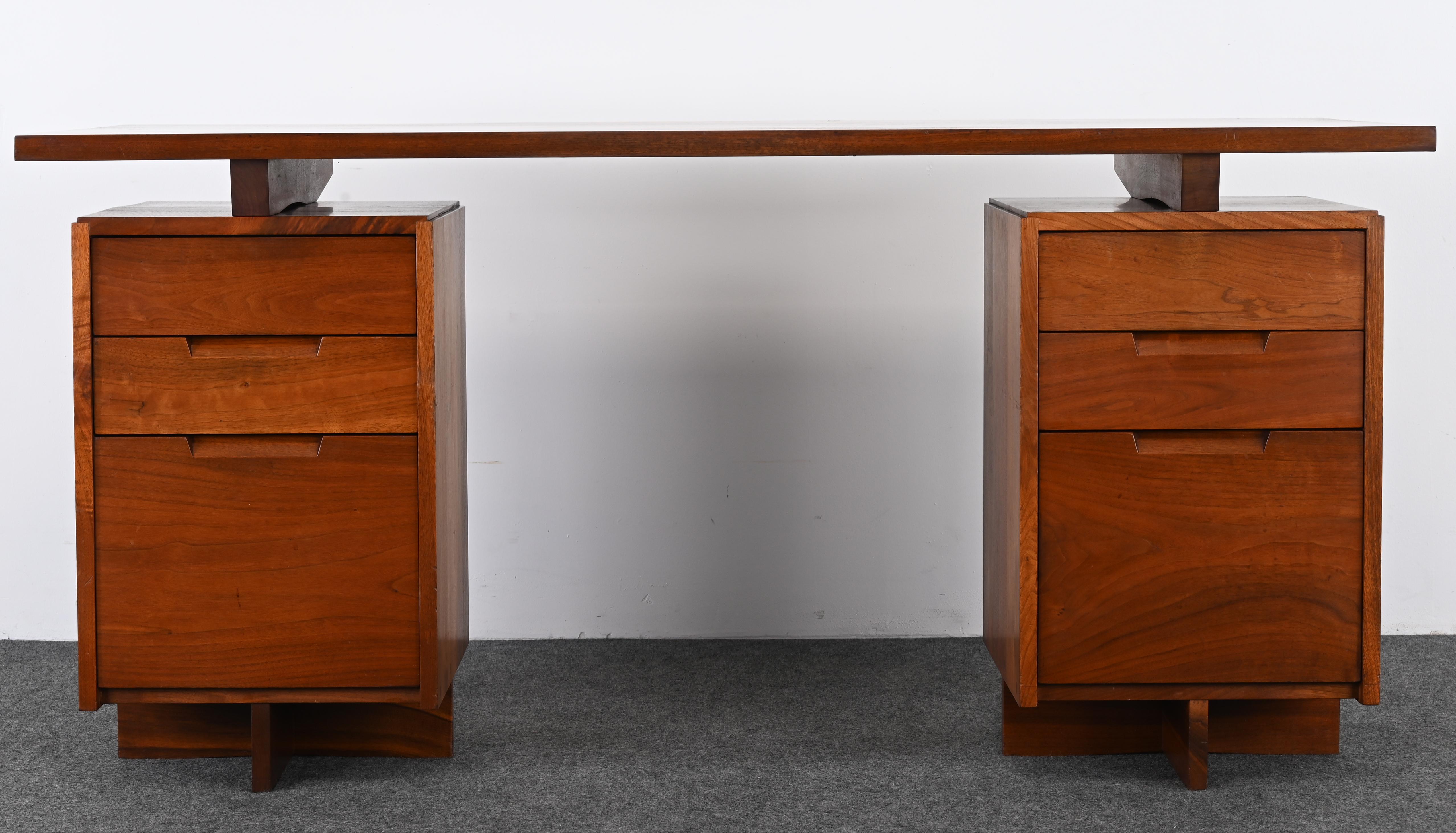 Una scrivania a doppio piedistallo e una sedia da capitano in noce nero di George Nakashima.
La scrivania è stata realizzata per la prima volta nel 1955, mentre questa è stata prodotta nel 1961.
Entrambi i pezzi conservano i nomi originali dei